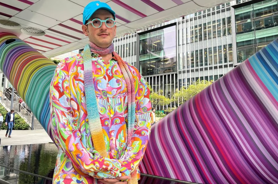 Artist and designer Adam Nathaniel Furman poses next to "Click Your Heels Together Three Times," an art installation they designed in Canary Wharf, where they added technicolor stripes to the underside and pillars of a bridge in London, Britain, Sept. 19, 2023.