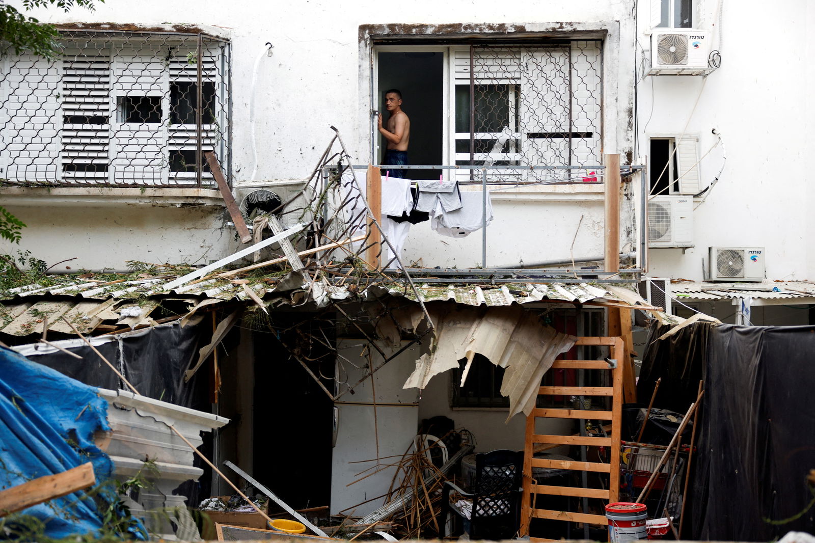 An Israeli man looks out from a window of a building that was hit following rockets from Gaza that were launched towards Israel in Ashkelon, southern Israel October 9, 2023. 