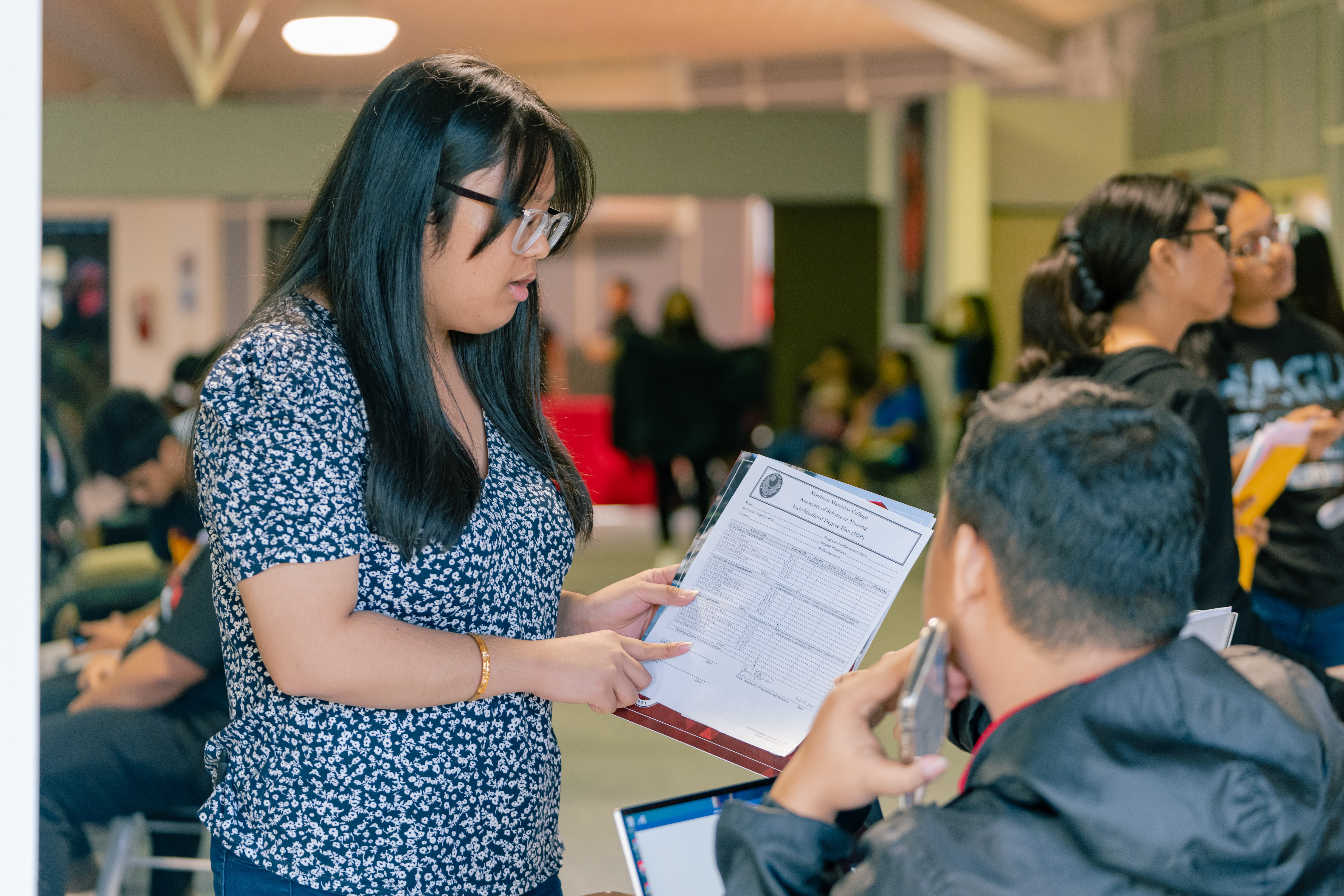 A community member speaks with a Northern Marianas College representative at an NMC info session on June 28, 2023.