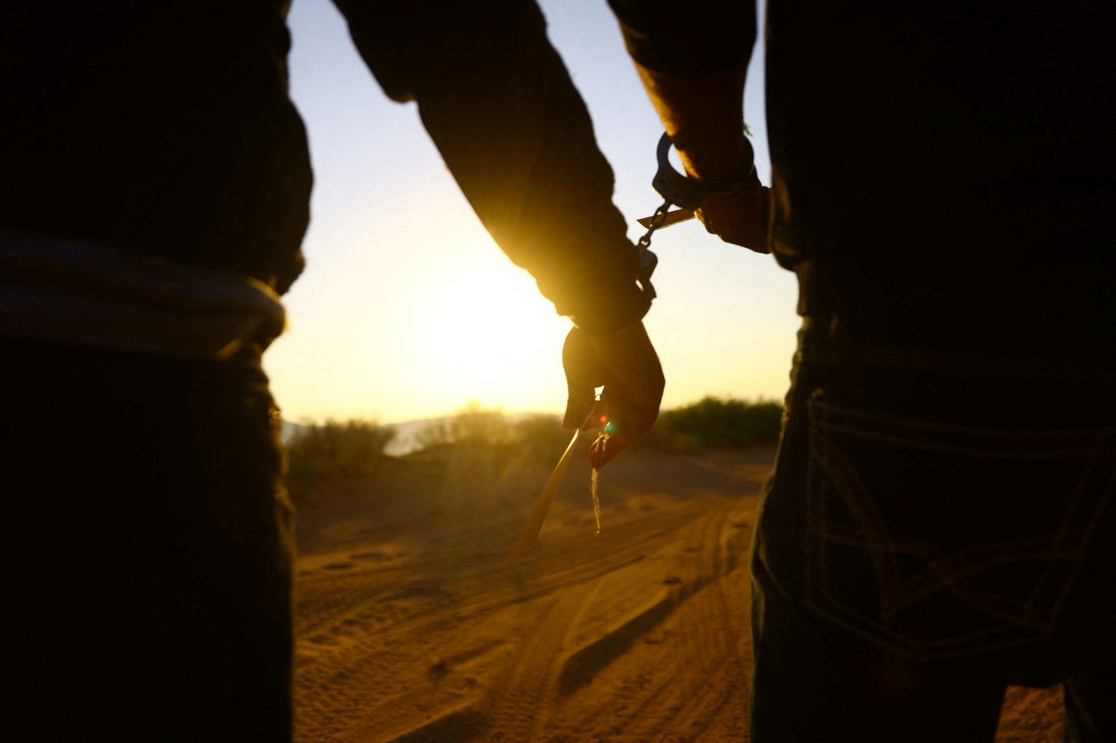 Migrants, who attempted to cross the U.S.-Mexico border without being detected, walk in handcuffs after being detained by U.S. Border Patrol agents in the desert of Sunland Park, New Mexico, U.S. June 23, 2023. REUTERS/Jose Luis Gonzalez