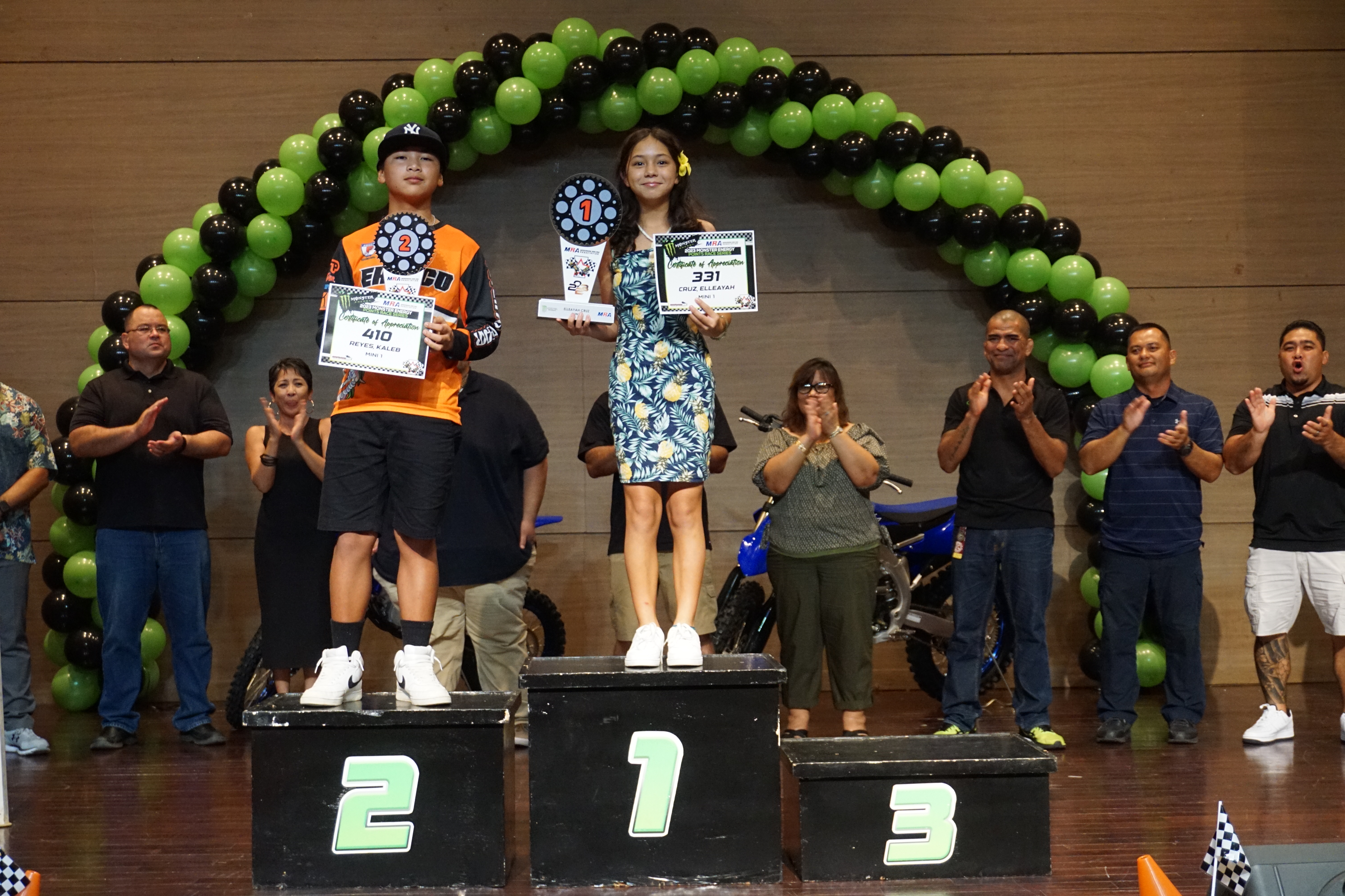 Elleayah Cruz, center, and Kaleb Reyes pose for a photo with their trophies in the Mini 1 class of the 2023 MRA Monster Energy Points Race Series during the awards ceremony on Sept. 30 at the Saipan World Resort Taga Hall.