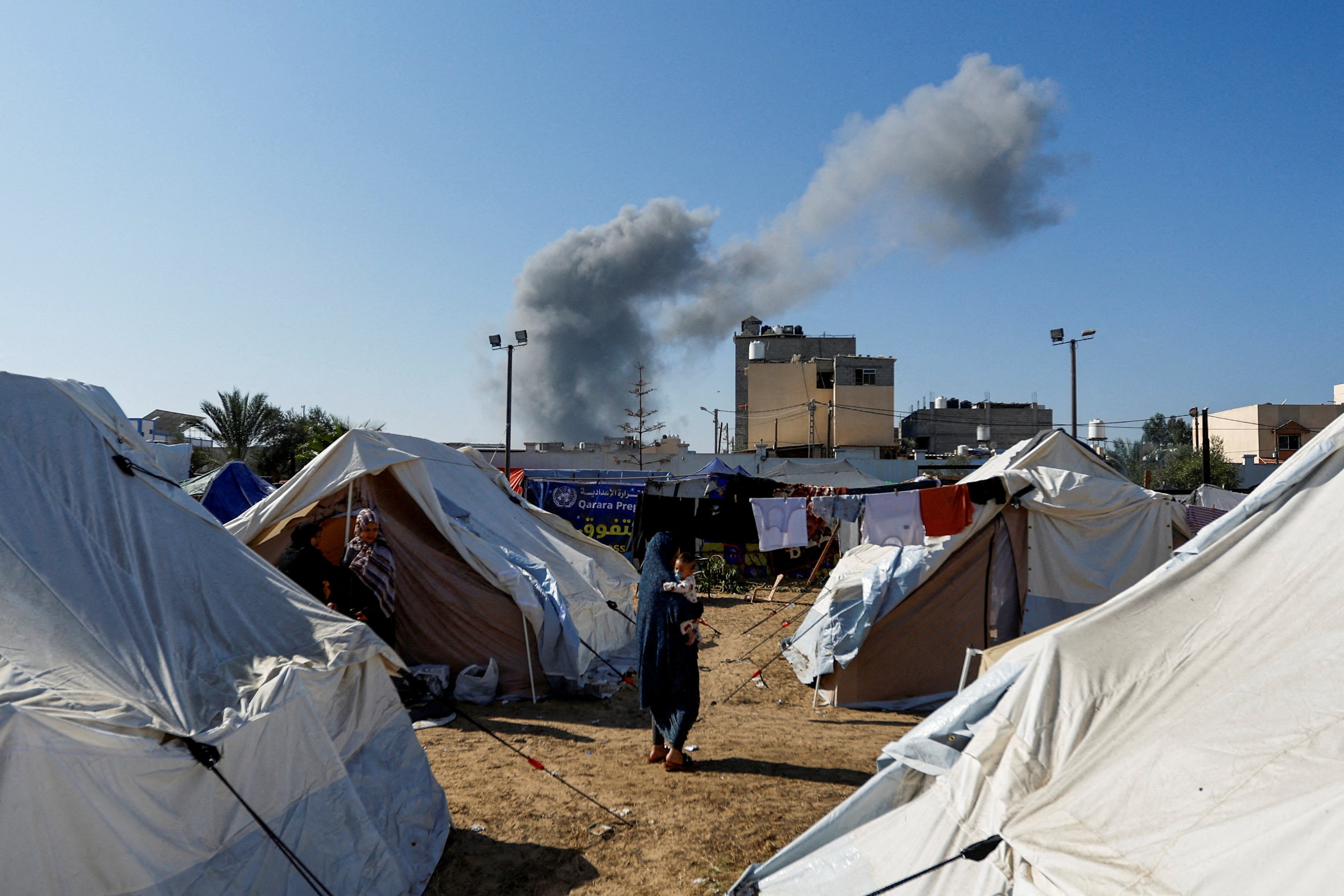 Smoke rises from nearby Israeli strikes as seen from a tent camp sheltering displaced Palestinians, as the conflict between Israel and Palestinian Islamist group Hamas continues, in Khan Younis in the southern Gaza Strip, October 26, 2023. 