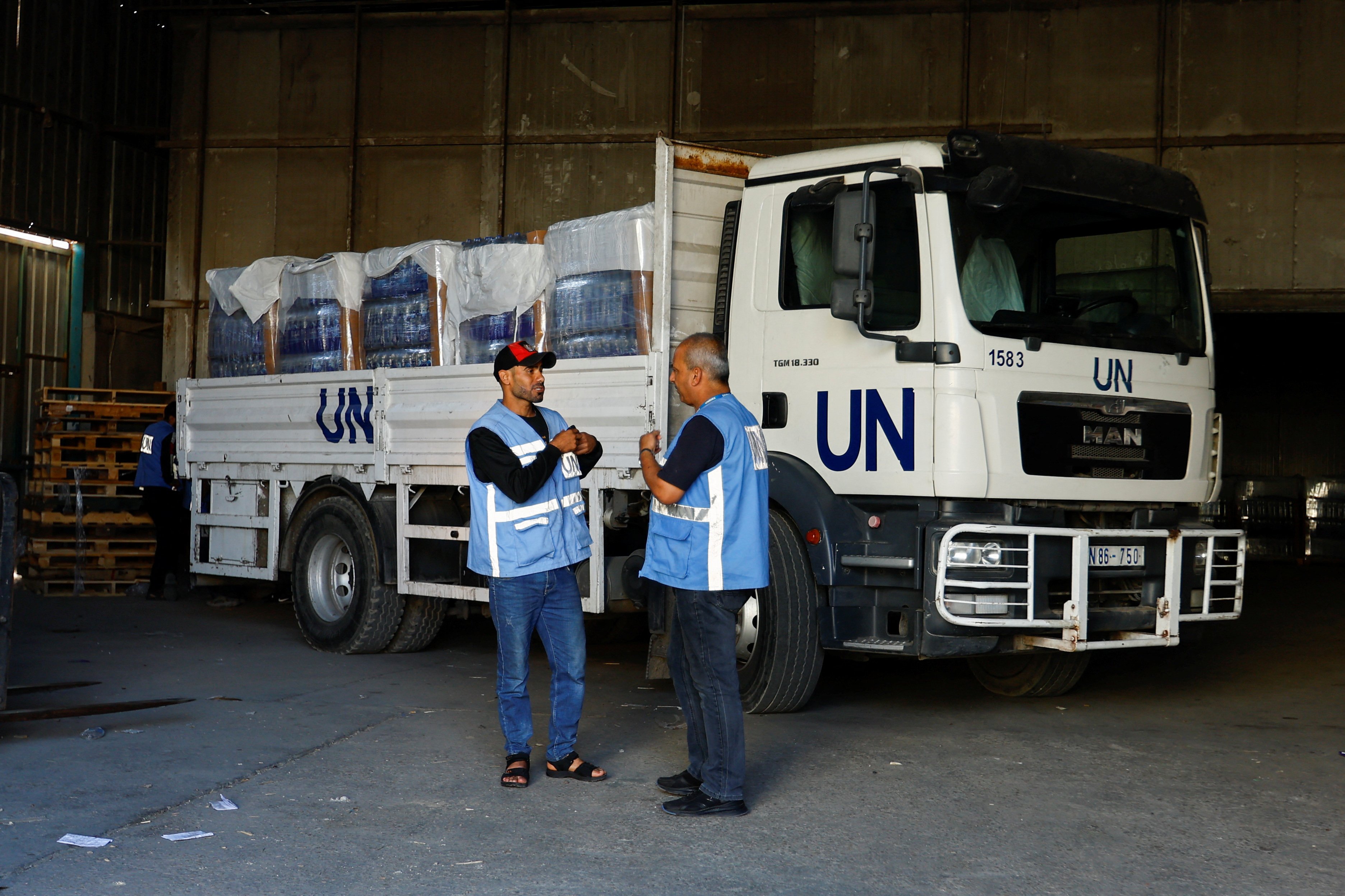 Workers stand by a United Nations vehicle, while sorting aid to be distributed to Palestinians, as the conflict between Israel and Palestinian Islamist group Hamas continues, at a United Nations-run facility, in Khan Younis in the southern Gaza Strip, October 26, 2023. 