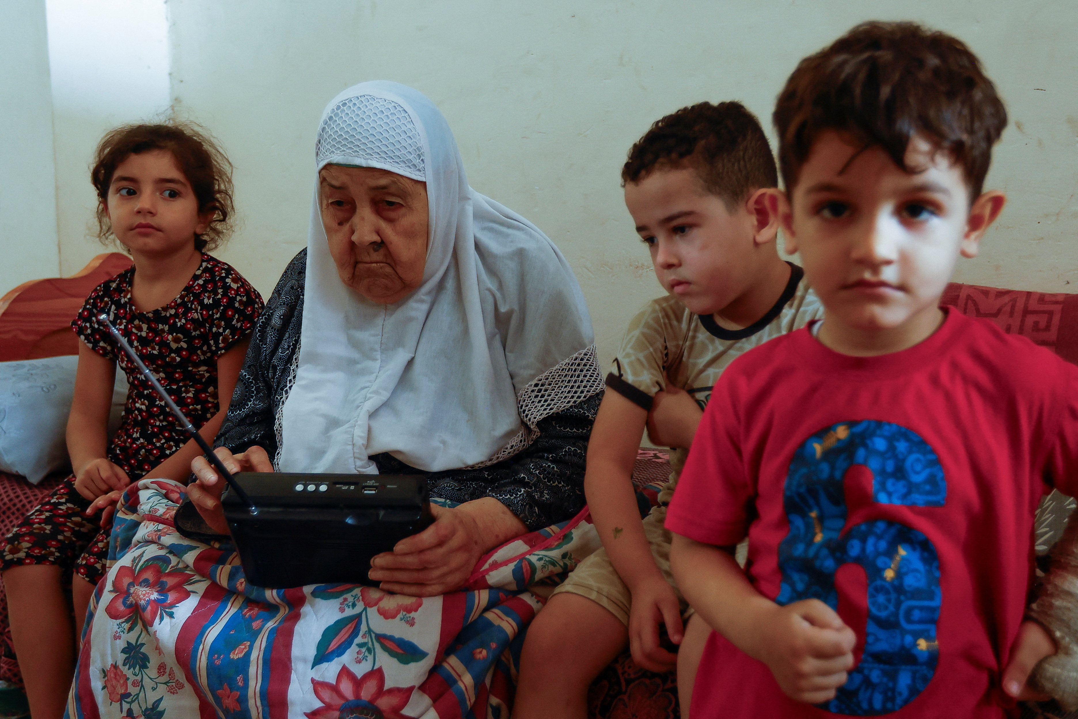 Palestinian woman Fawzeya Shaheen, 90, who lived through all Israeli-Palestinian wars dating back to 1948, sits with her grandchildren at her home, amid the ongoing Israeli-Palestinian conflict, in Khan Younis in the southern Gaza Strip October 14, 2023. REUTERS/Ibraheem Abu Mustafa