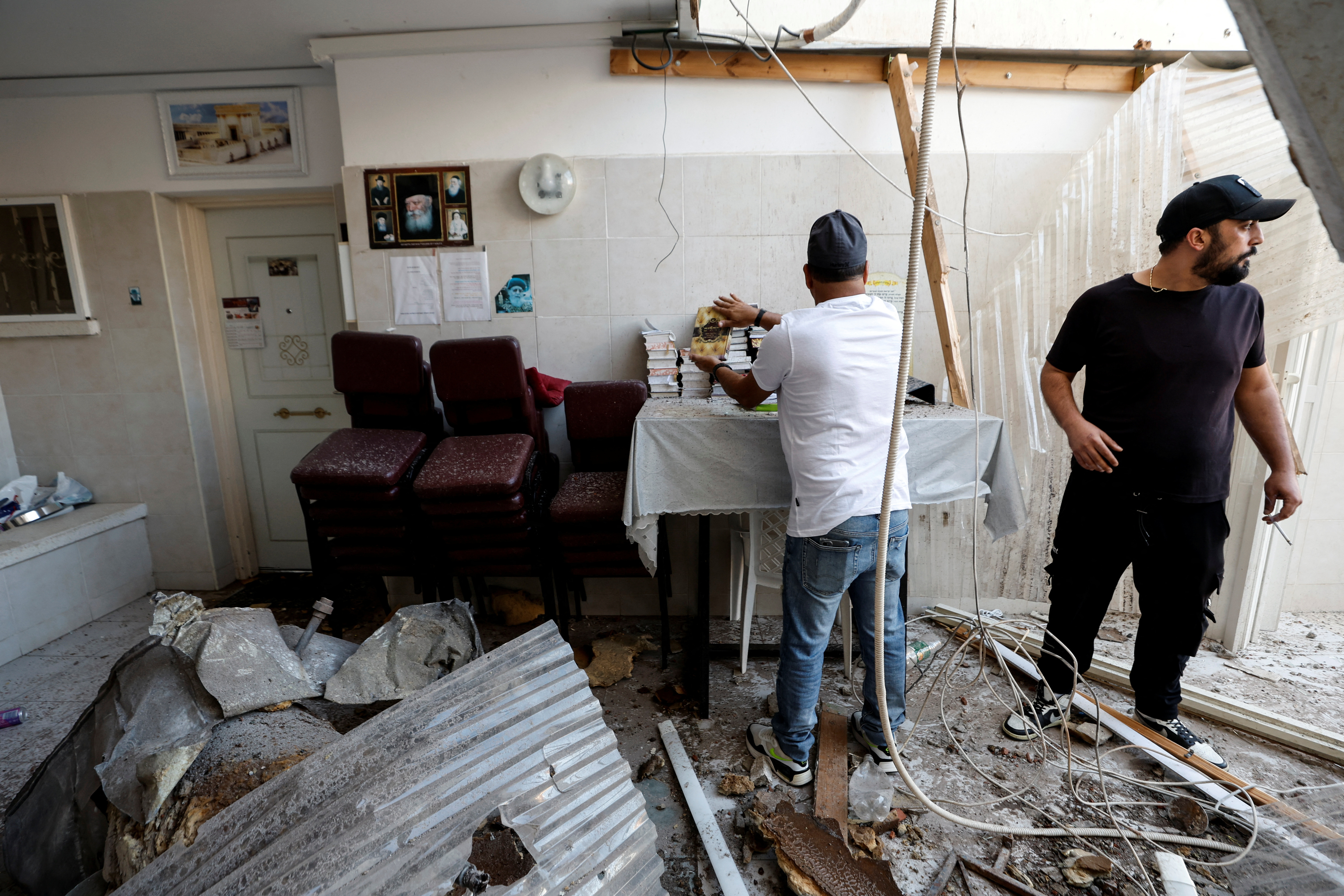 A man organises Jewish prayer books after a synagogue was hit by a rocket launched from the Gaza Strip into Israel, in Ashkelon, southern Israel October 15, 2023. 