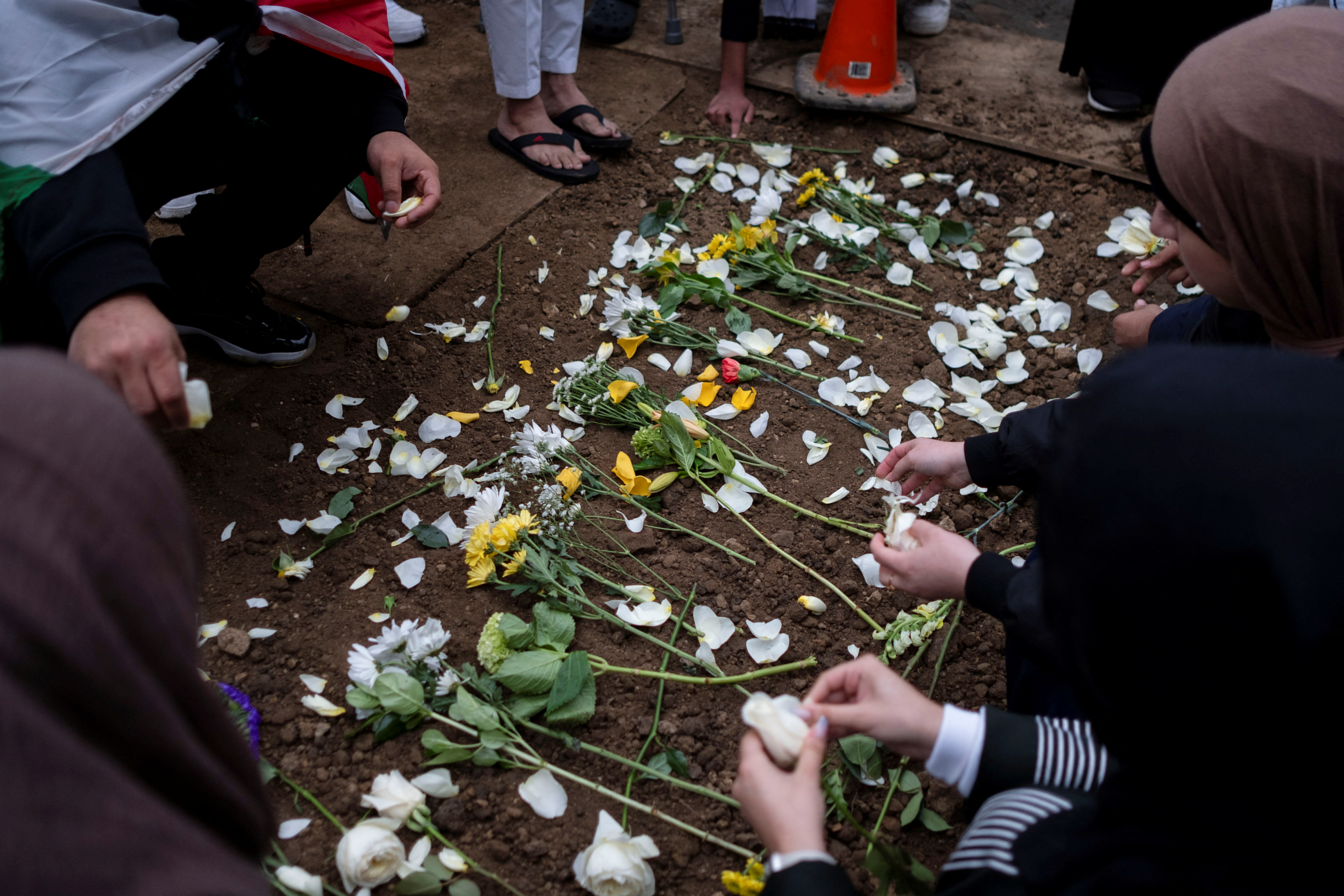Mourners place flowers at the grave of Wadea Al-Fayoume at Parkholm Cemetery where the burial took place of Wadea Al-Fayoume, 6, a Muslim boy who according to police was stabbed to death in an attack that targeted him and his mother for their religion and as a response to the war between Israel and Hamas, in LaGrange, Illinois, U.S. October 16, 2023. 