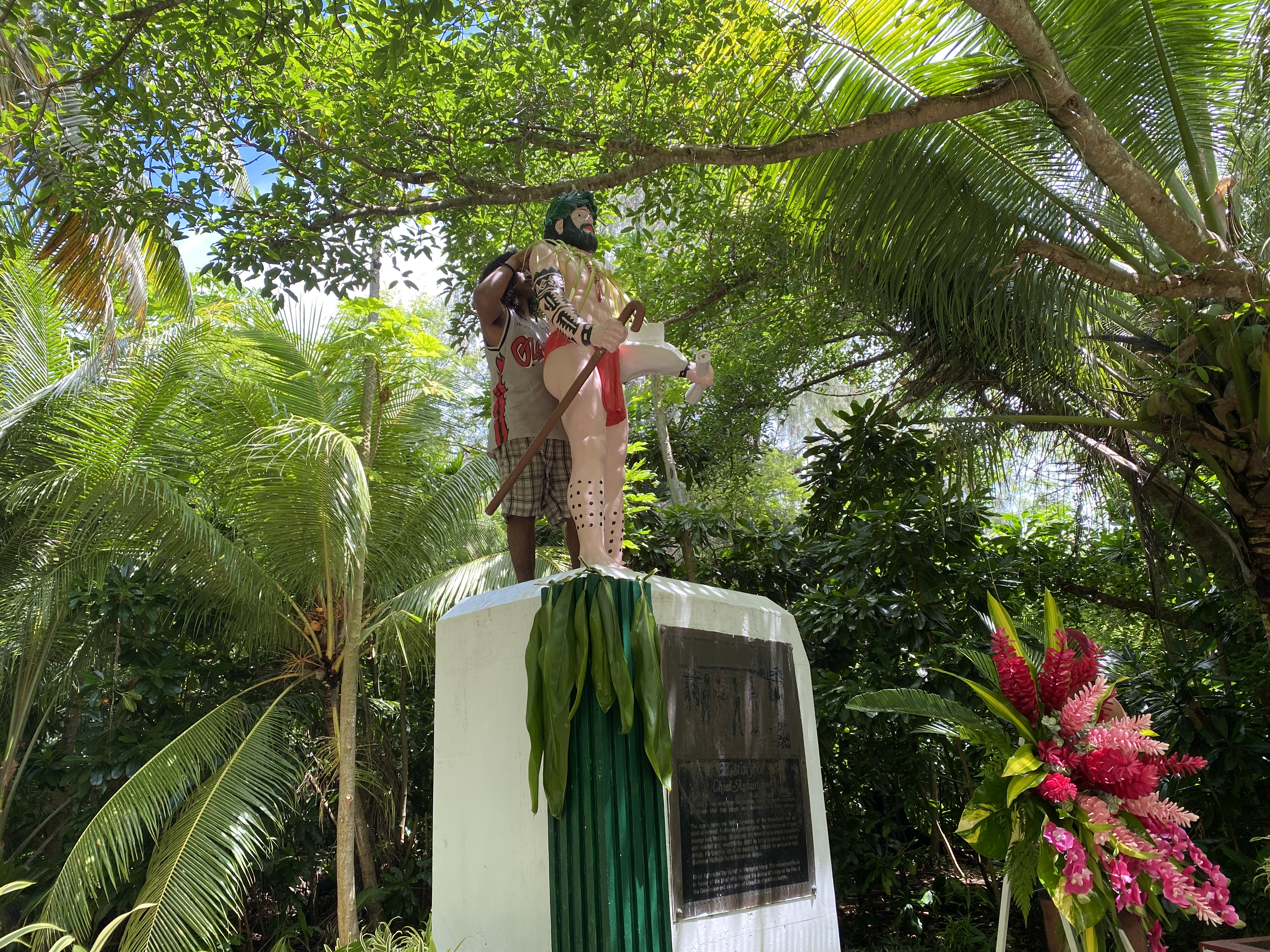 A man places woven coconut leaves on the statute of Chief Aghurubw.
