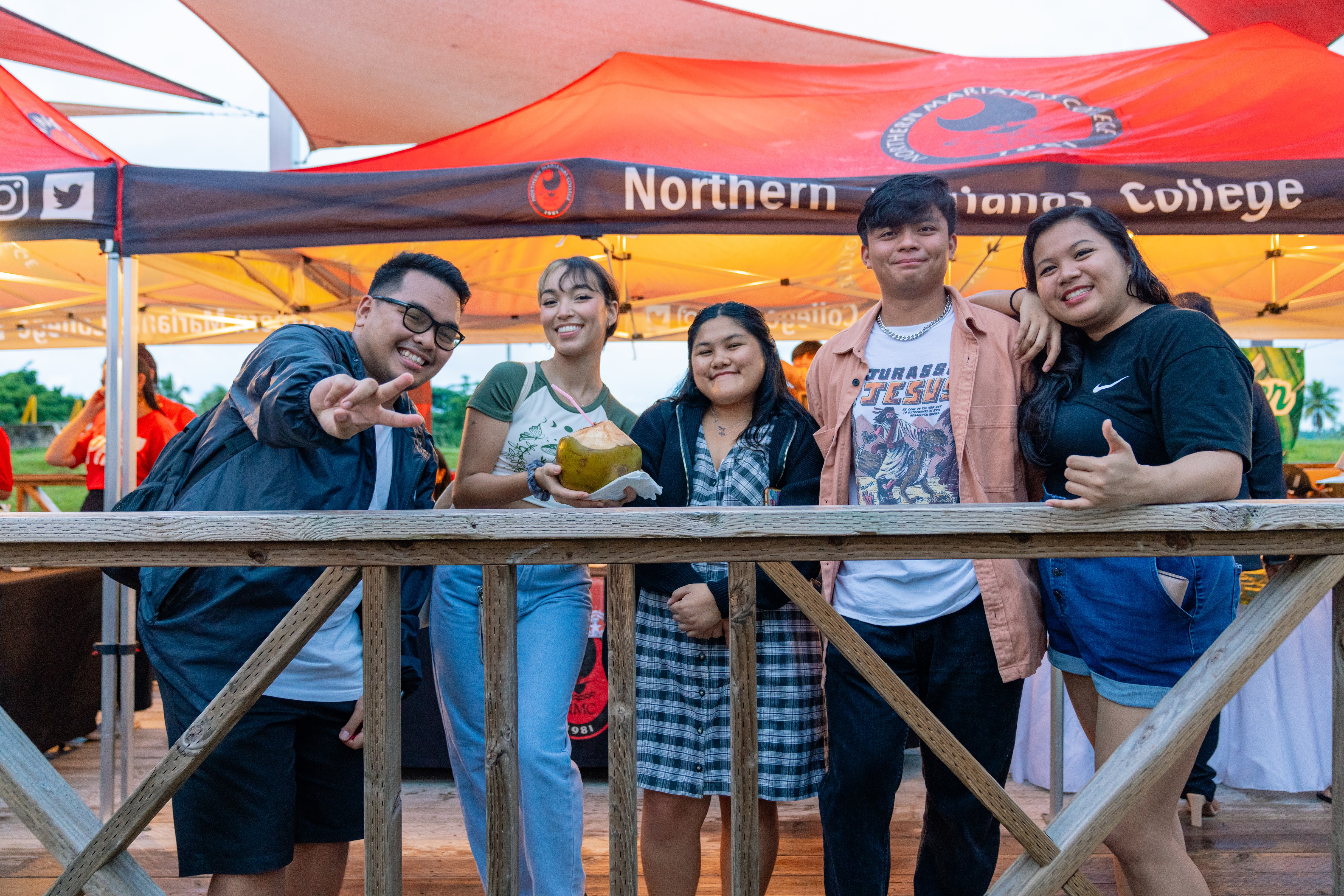 NMC alumni pose for a group photo in front of local vendors at Mango Terrace.