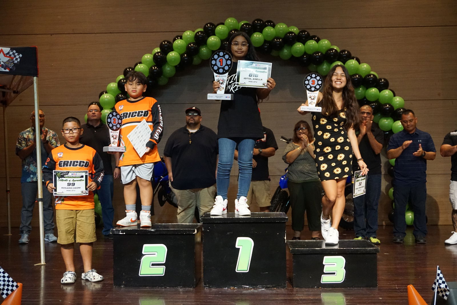 Anella Igitol displays the first-place trophy as she poses for a photo with the other Mini ATV Class participants of the 2023 Marianas Racing Association Monster Energy Points Race Series during the awards ceremony Saturday at the Saipan World Resort Taga Hall.