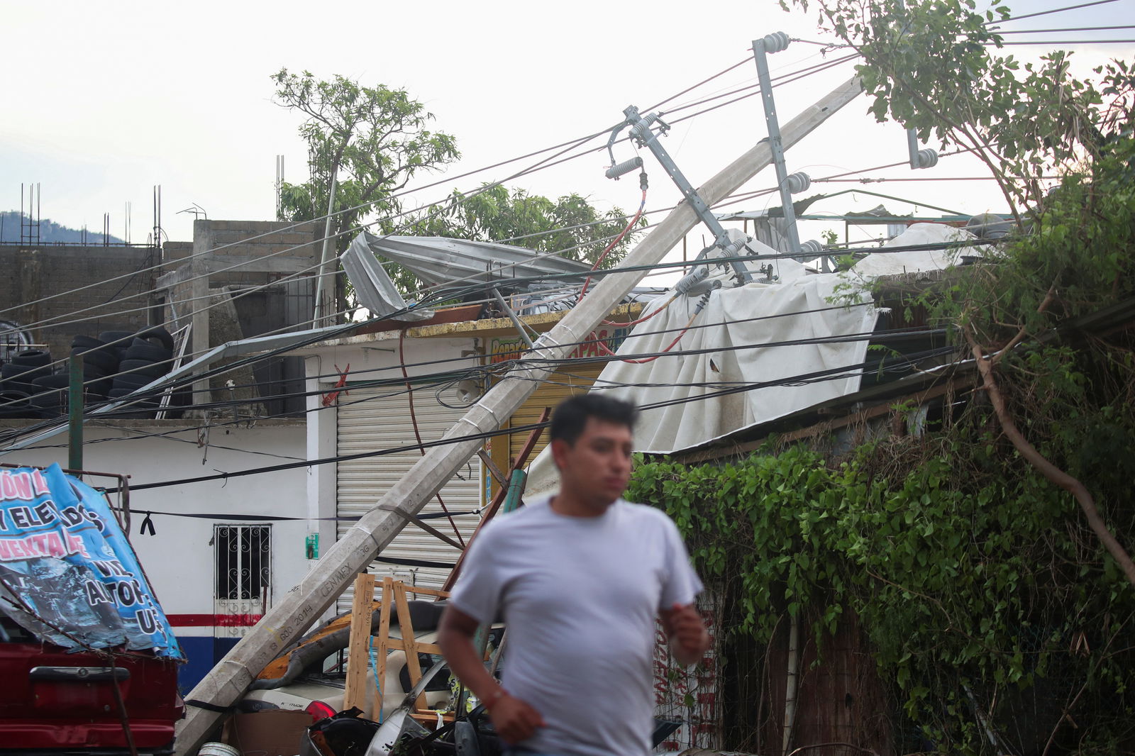 A man runs past a fallen electricity pole near the entrance to Acapulco after Hurricane Otis hit, in the Mexican state of Guerrero, Mexico October 25, 2023. 