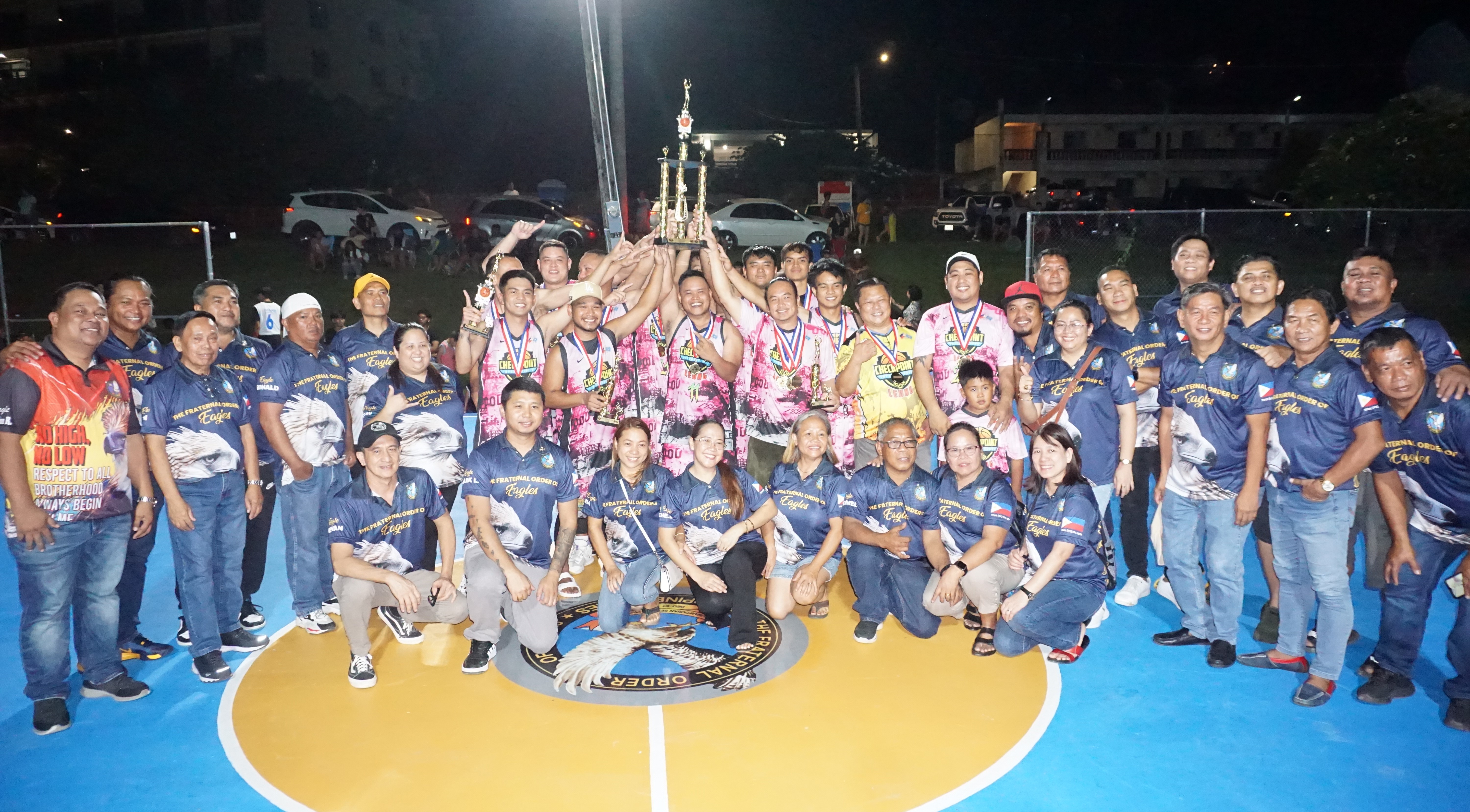 Team Checkpoint players display the open division championship trophy as they pose for a photo with officials of the 2023 Saipan Magalahi Eagles Club Invitational Basketball League on Saturday at the Gualo Rai basketball court.
