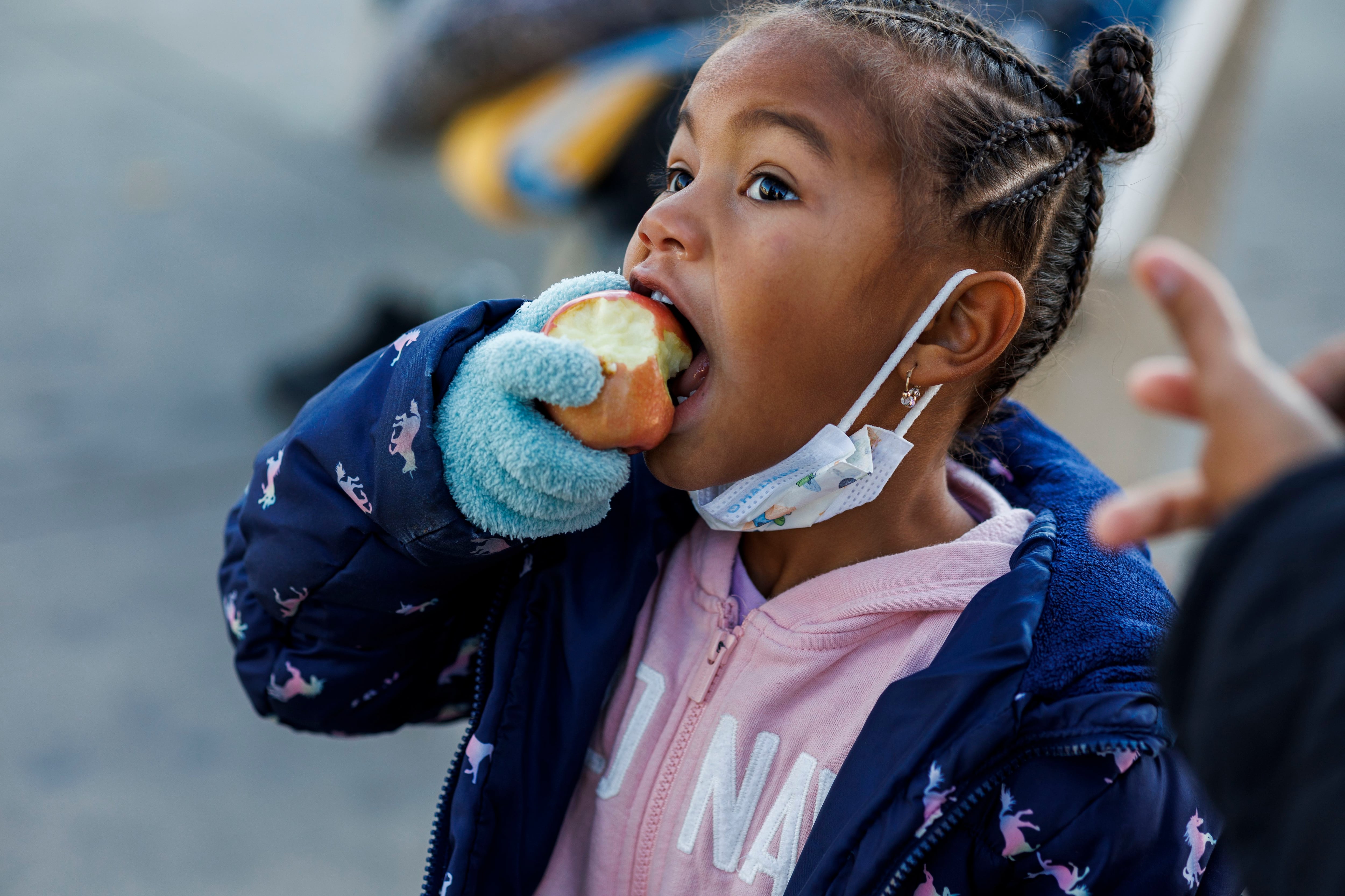 Venezuelan migrant Jessmar, 4, eats an apple after her mother, Jessana Malaue, 27, purchased food at a WIC grocery on West Cermak Road in Chicago on Nov. 10, 2023. Malaue purchased three bags of produce from the WIC grocery due to shelter restrictions that limit migrants from keeping food that can’t fit in a backpack under their cots.