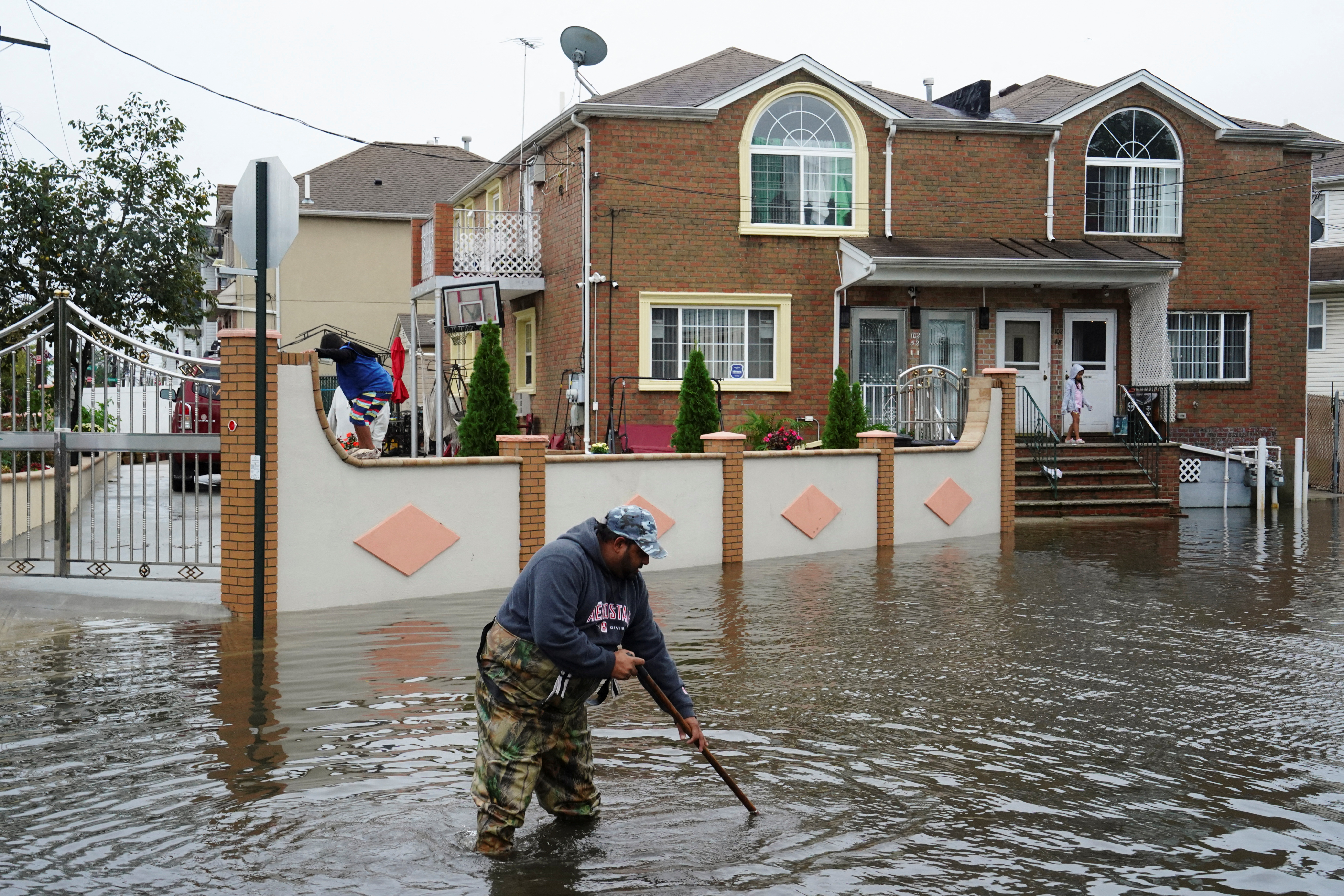 A resident surnamed Mahamad, a driving instructor and bus driver, attempts to unclog leaves and other debris from drainage holes in the flooded street of Rau Court, as the remnants of Tropical Storm Ophelia bring flooding across the mid-Atlantic and Northeast, in the Hamilton Beach neighborhood in the Queens borough of New York City, U.S., September 29, 2023. 