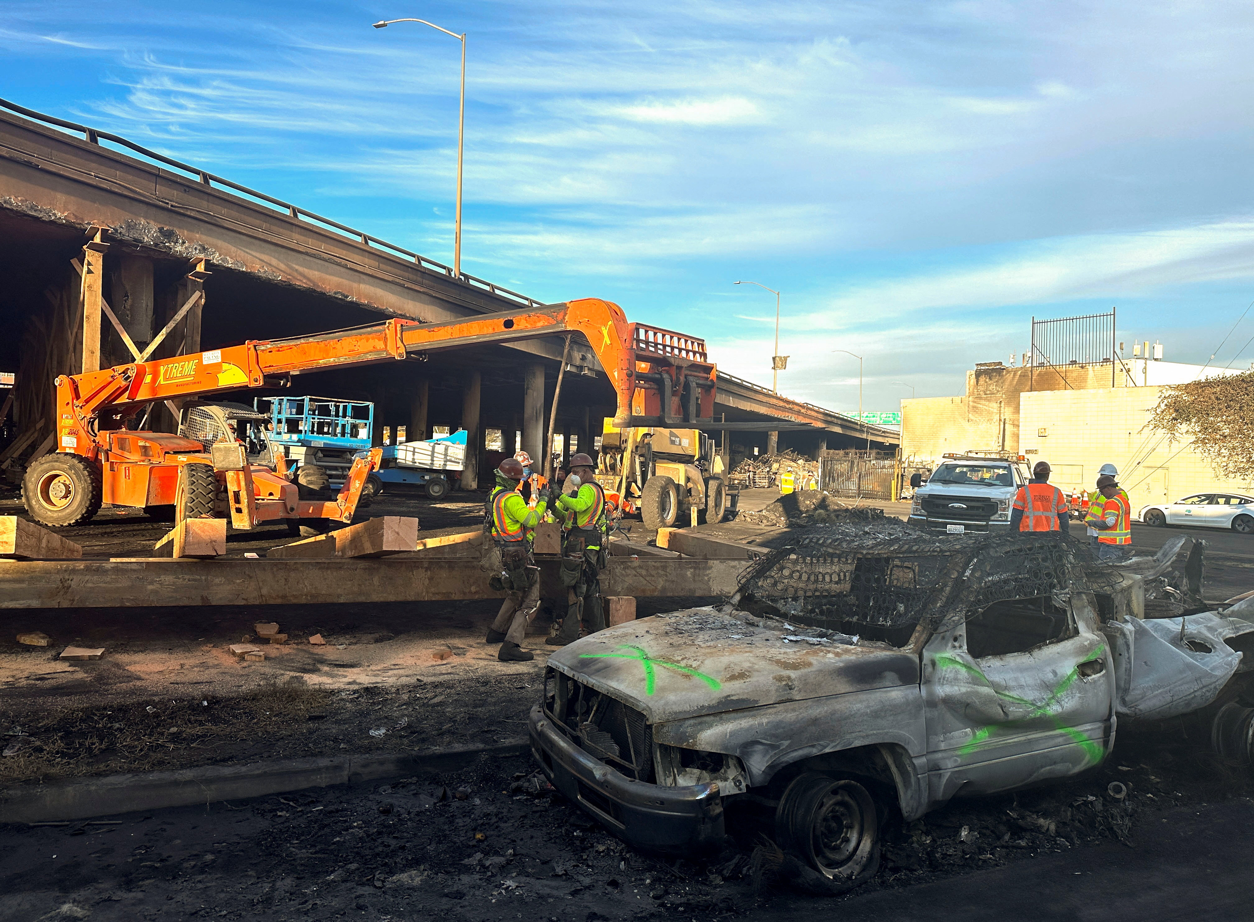Crew members work in the area, where a fire erupted over the weekend, shutting down a heavily trafficked corridor in Los Angeles, California, U.S., November 13, 2023. 