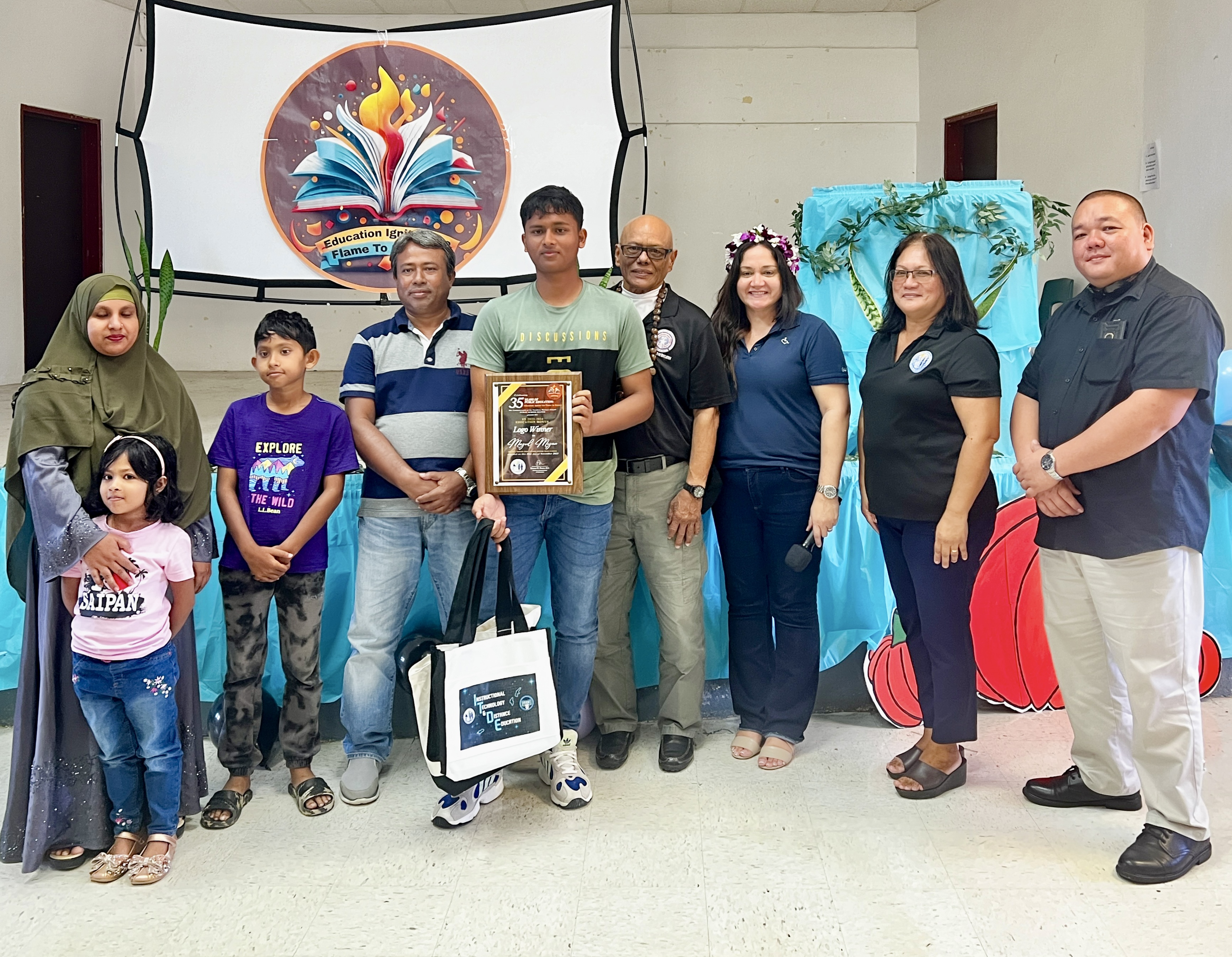 Dr. Rita Hocog Inos Junior Senior High School 11th grader Mazed Mizan is this year’s Public School System  logo winner. He was presented with his award by Board of Education Vice Chair Herman Atalig, Interim Com​missioner of Education Donna M. Flores, Associate Commissioner for Administrative Services Eric Magofna, and Principal Annette Calvo. Also in photo are Mizan’s parents and siblings.