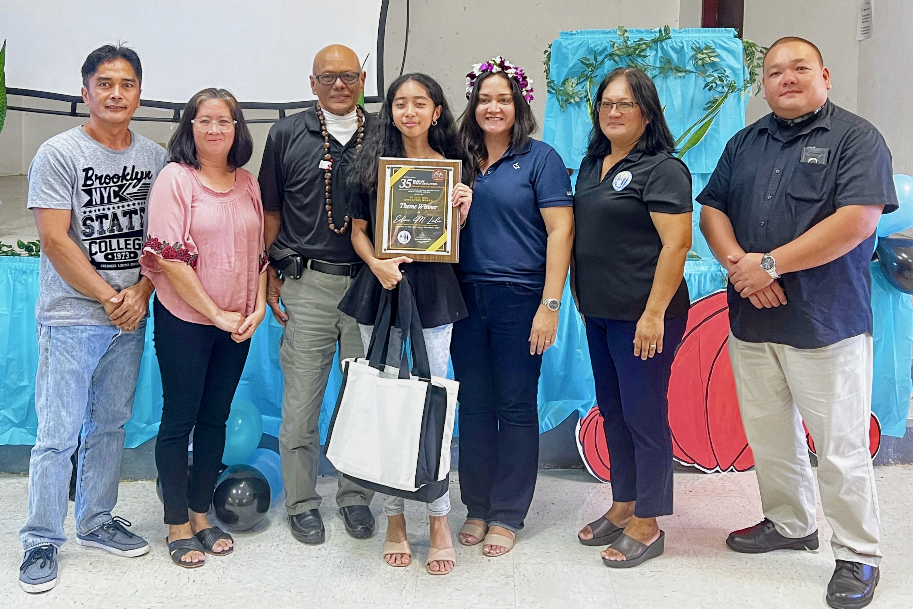 Board of Education Vice Chairperson Herman T. Atalig, Dr. Rita Hocog Inos Junior-Senior High School Principal Annette Calvo, Interim Commissioner of Education Donna M. Flores and Associate Commissioner for Administrative Services Eric Magofna present an award to Éclair M. Ladao, the 12th grader who won the 35th Education Day theme competition. With Ladao are her parents.