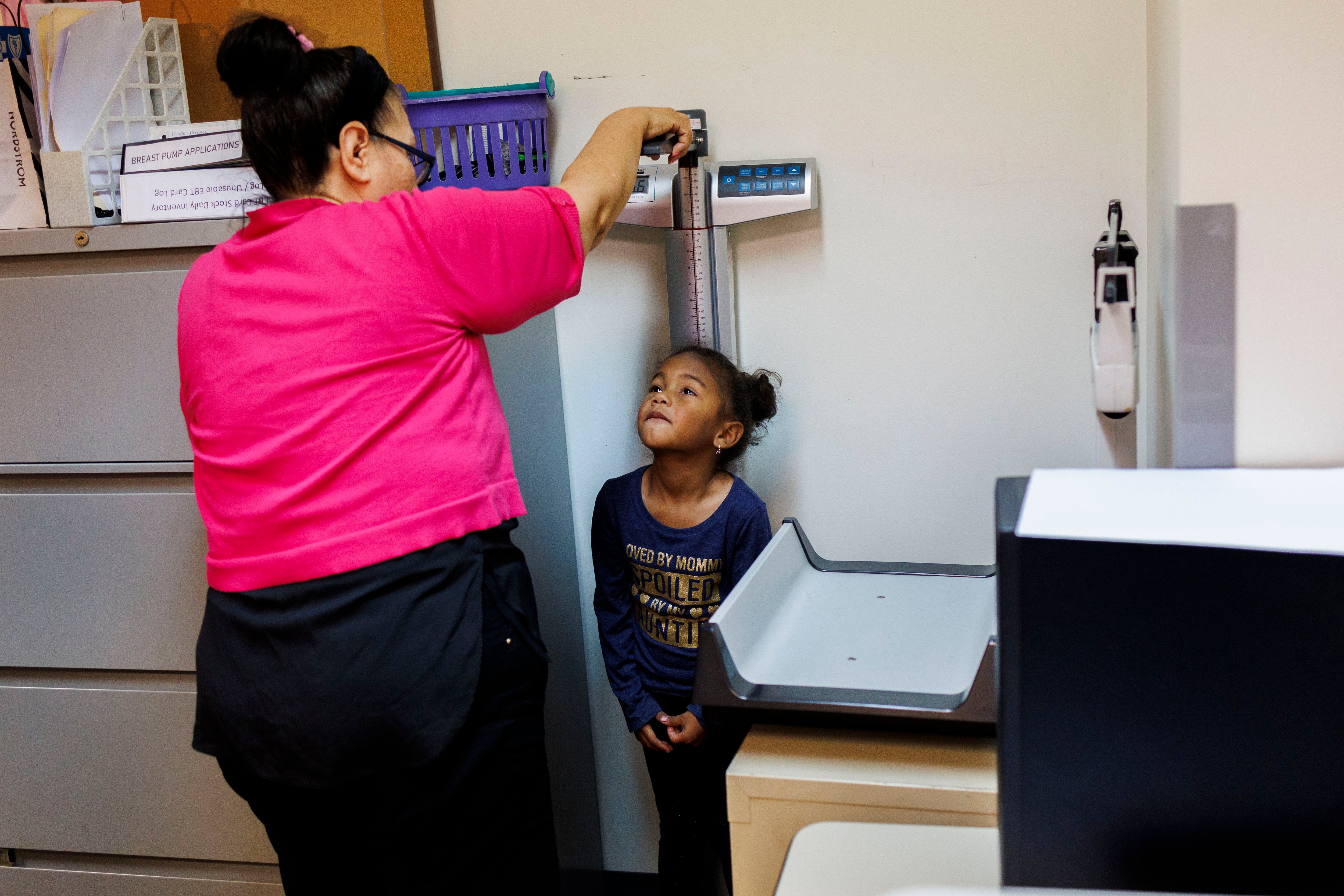 Rosa Pedroza measures 4-year-old Jessma’s height and weight while her mother, Jessana Malaue, 27, enrolls in the supplemental nutrition program for women, infants and children at Near North Health center on Nov. 1, 2023.