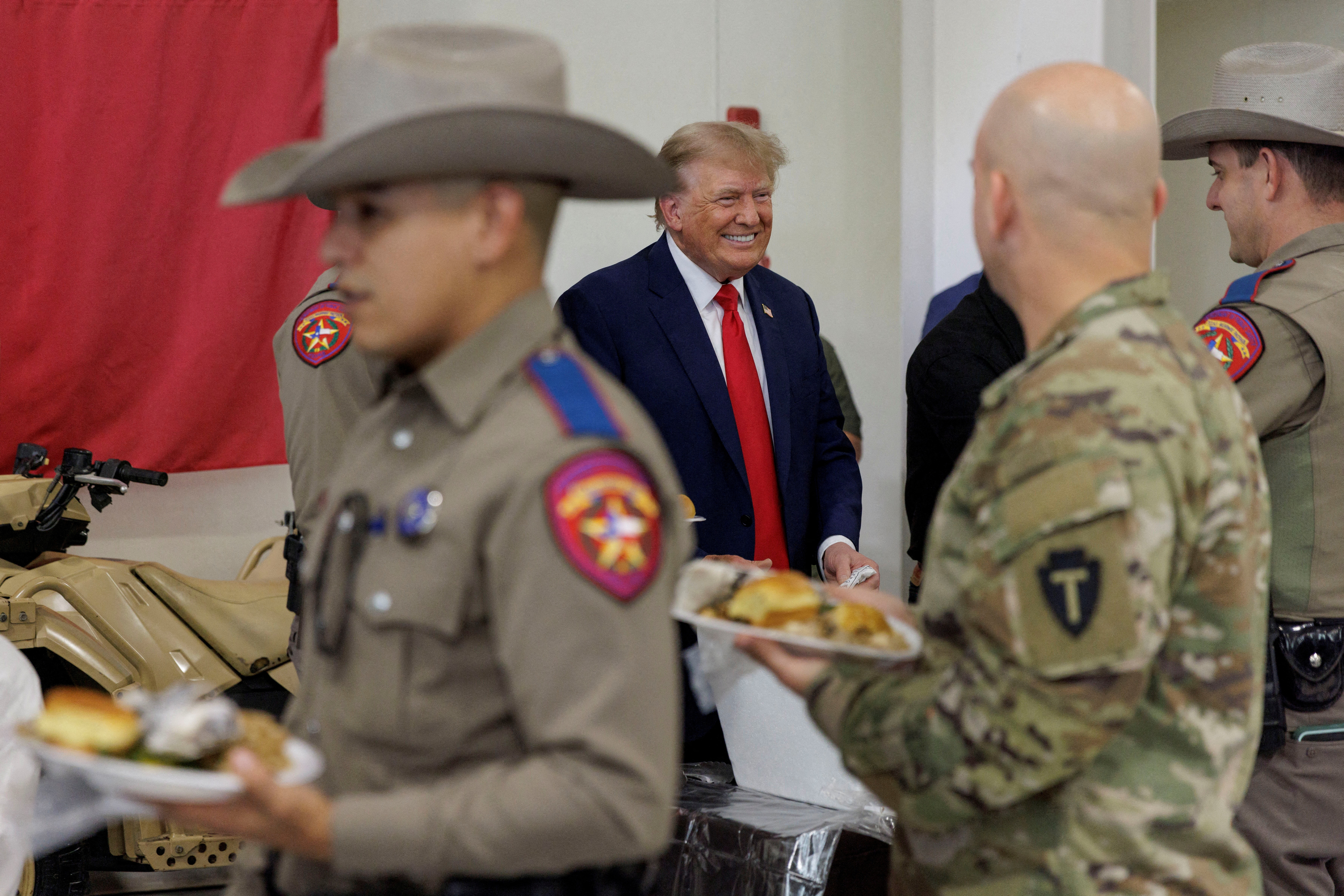 Republican presidential candidate and former U.S. President Donald Trump speaks with Texas DPS troopers at the South Texas International airport in Edinburg, Texas, U.S. November 19, 2023. 