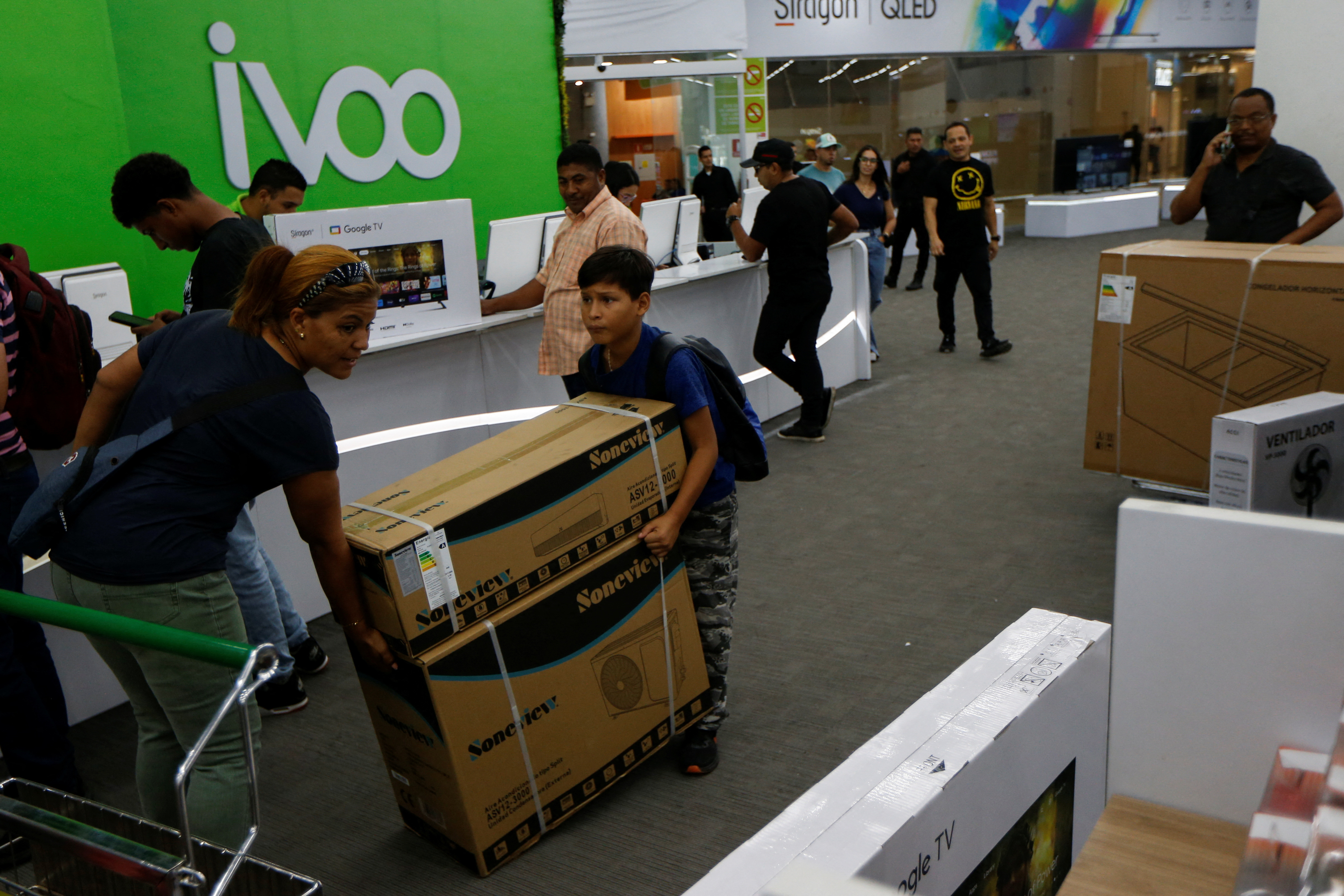 A mother and her son carry an air conditioning box during a Black Friday, in Caracas, Venezuela November 24, 2023. 