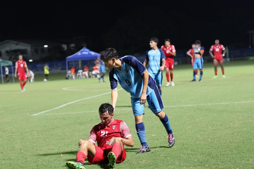 The NMI’s Akira Kadokura  helps  a Tahiti player get up after their collision during a football game in the 2023 Pacific Games on Saturday.