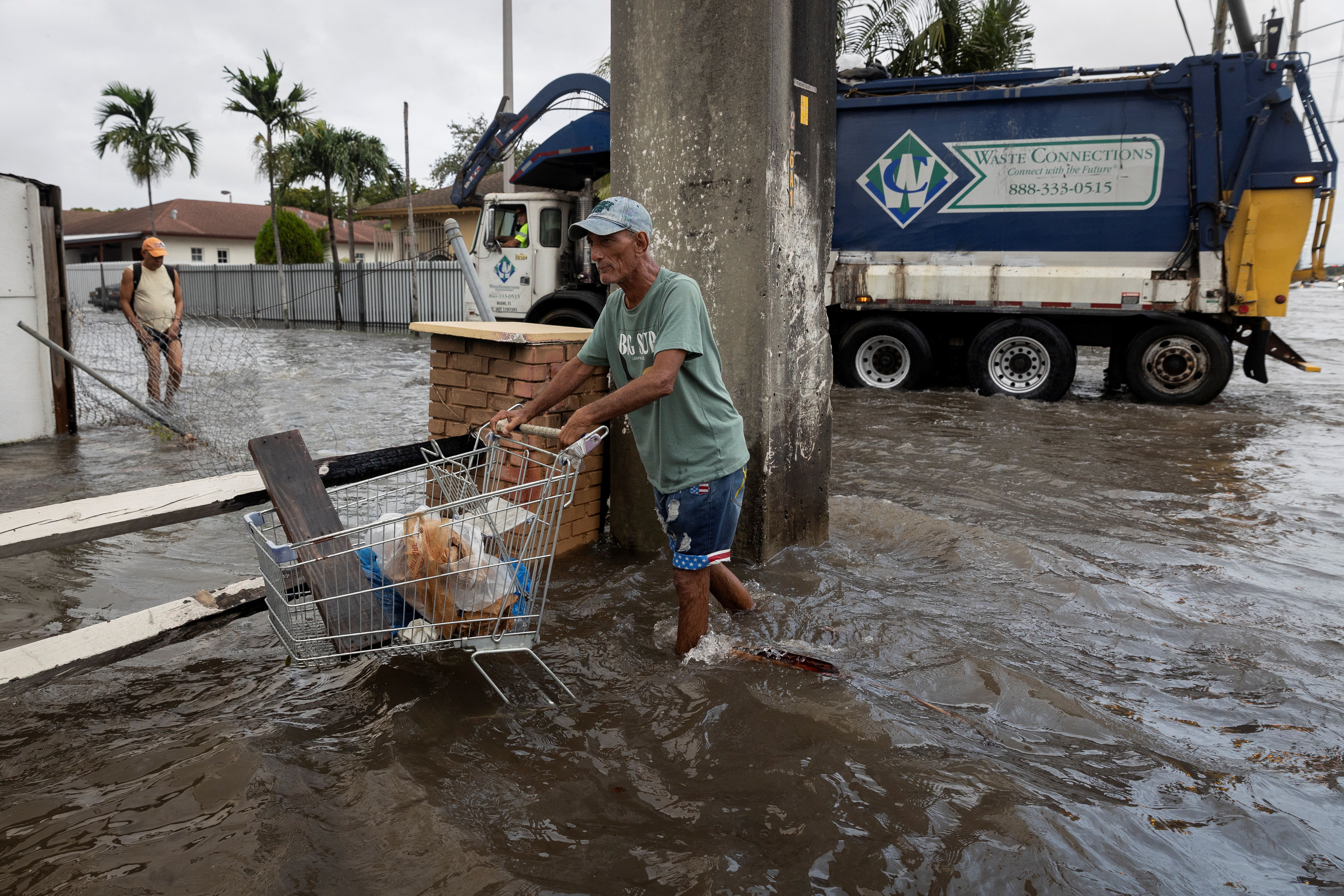 A man pushes a cart as he walks in a flooded street in Hialeah, Florida, U.S., November 16, 2023. 