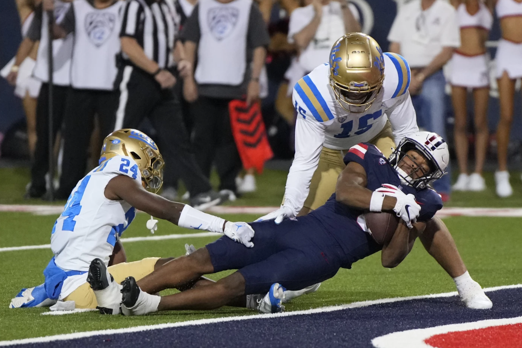 Arizona wide receiver Montana Lemonious-Craig (5) scores  a touchdown against UCLA defensive back Jaylin Davies (24) and defensive lineman Laiatu Latu during the first half of an NCAA college football game Saturday, Nov. 4, 2023, in Tucson, Ariz.