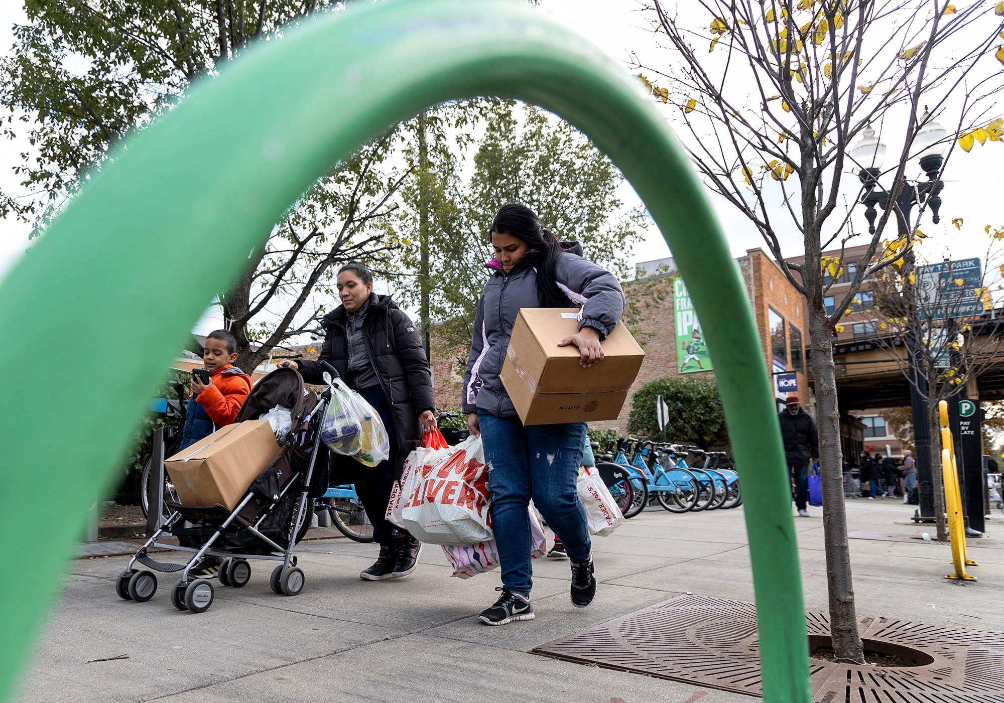 Families recently arrived from Venezuela carry bags of groceries they received from Nourishing Hope's Sheridan Market food pantry in Chicago on Nov. 10, 2023.