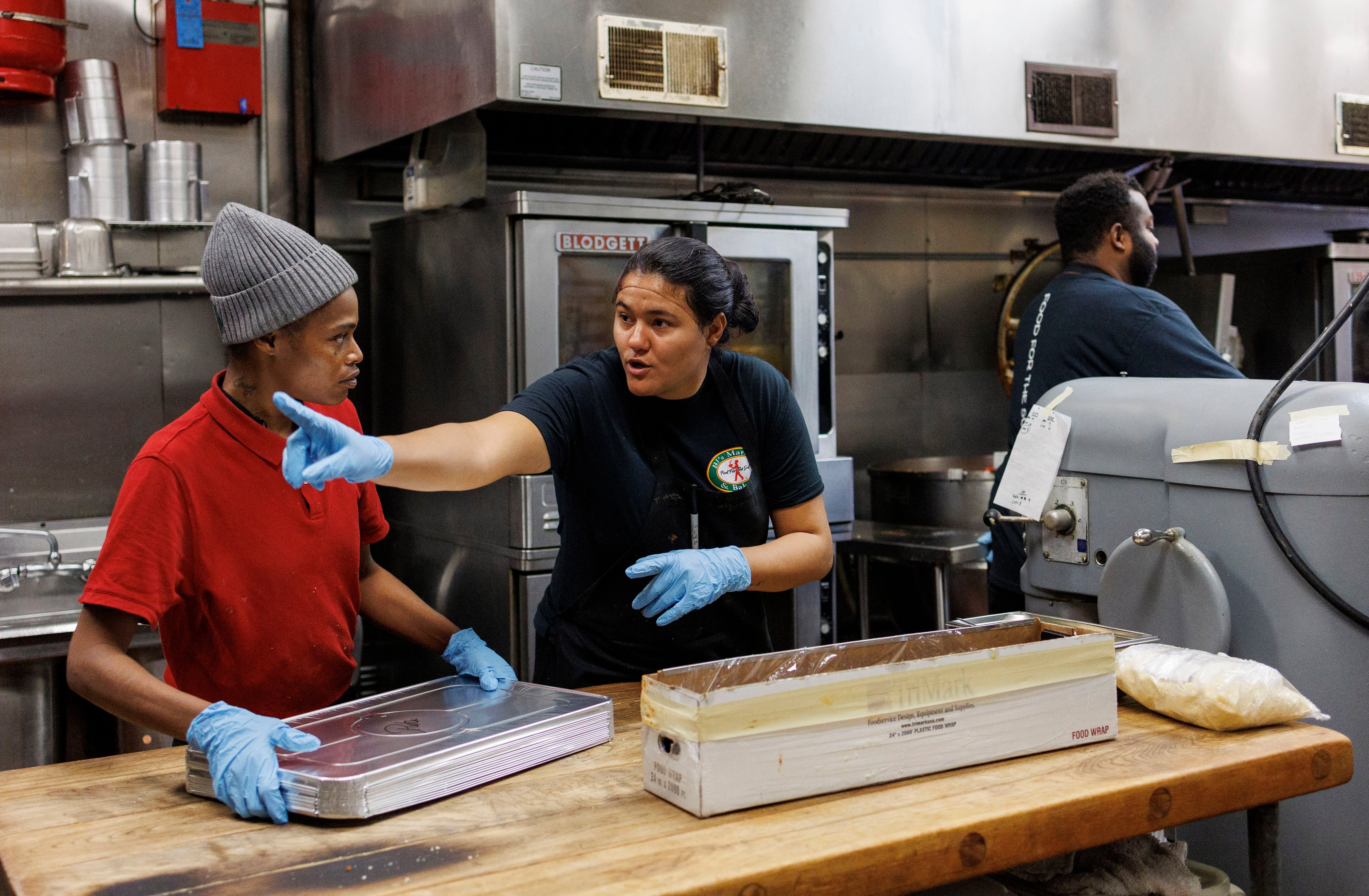 Mariana Vavalla, 29, a migrant from Venezuela, center, and Latoya Goodwin work in the kitchen at BJ’s Market in the South Deering neighborhood on Nov. 7, 2023. They spent the morning making spaghetti Bolognese for migrants staying at three shelters on the South Side.
