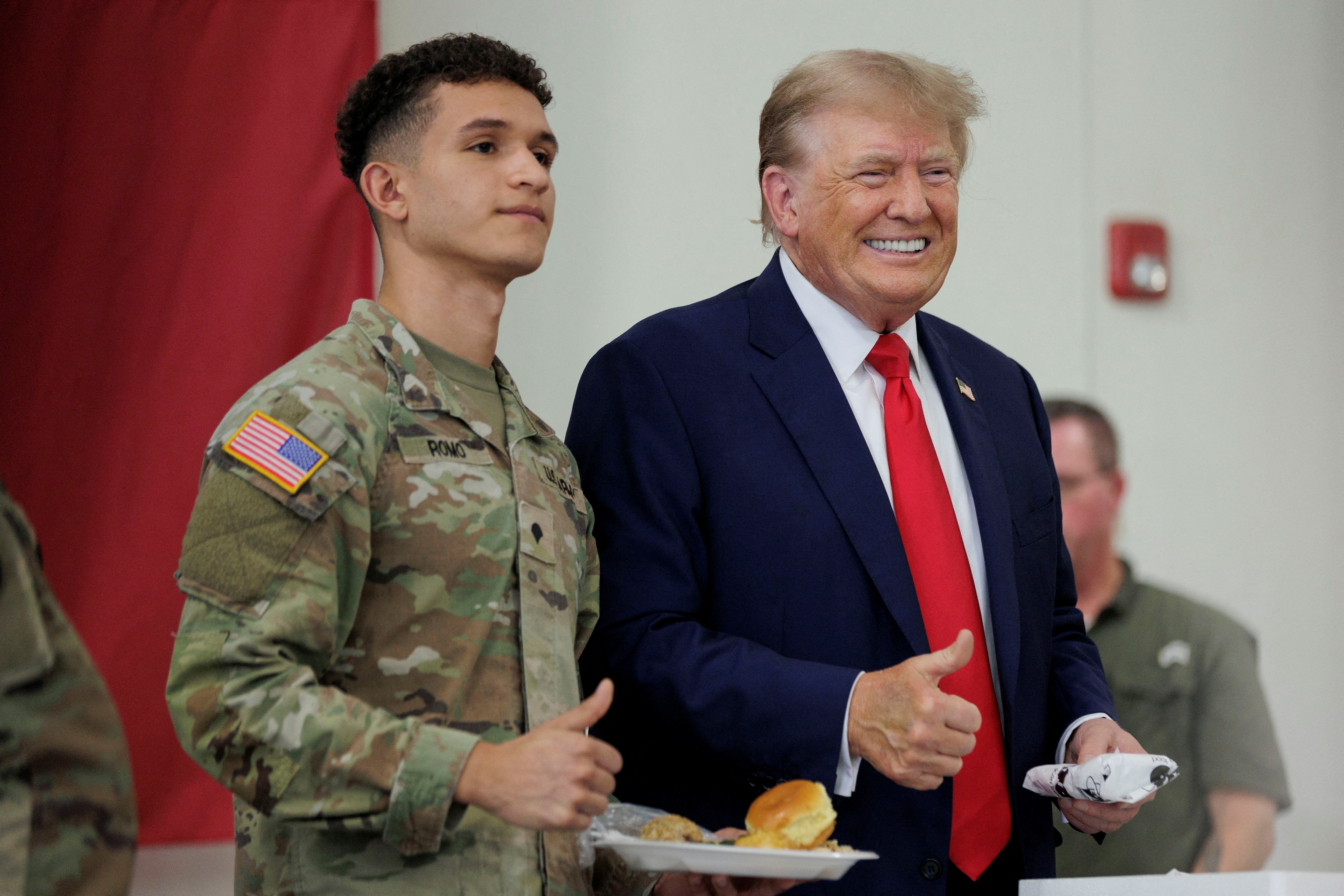 Former U.S. President Donald Trump poses for a photograph with a service member at the South Texas International airport in Edinburg, Texas, U.S. November 19, 2023. Trump and Texas Governor Greg Abbott served meals to Texas National Guard and Texas DPS Troopers that are stationed at the U.S.-Mexico border over the Thanksgiving holiday. 
