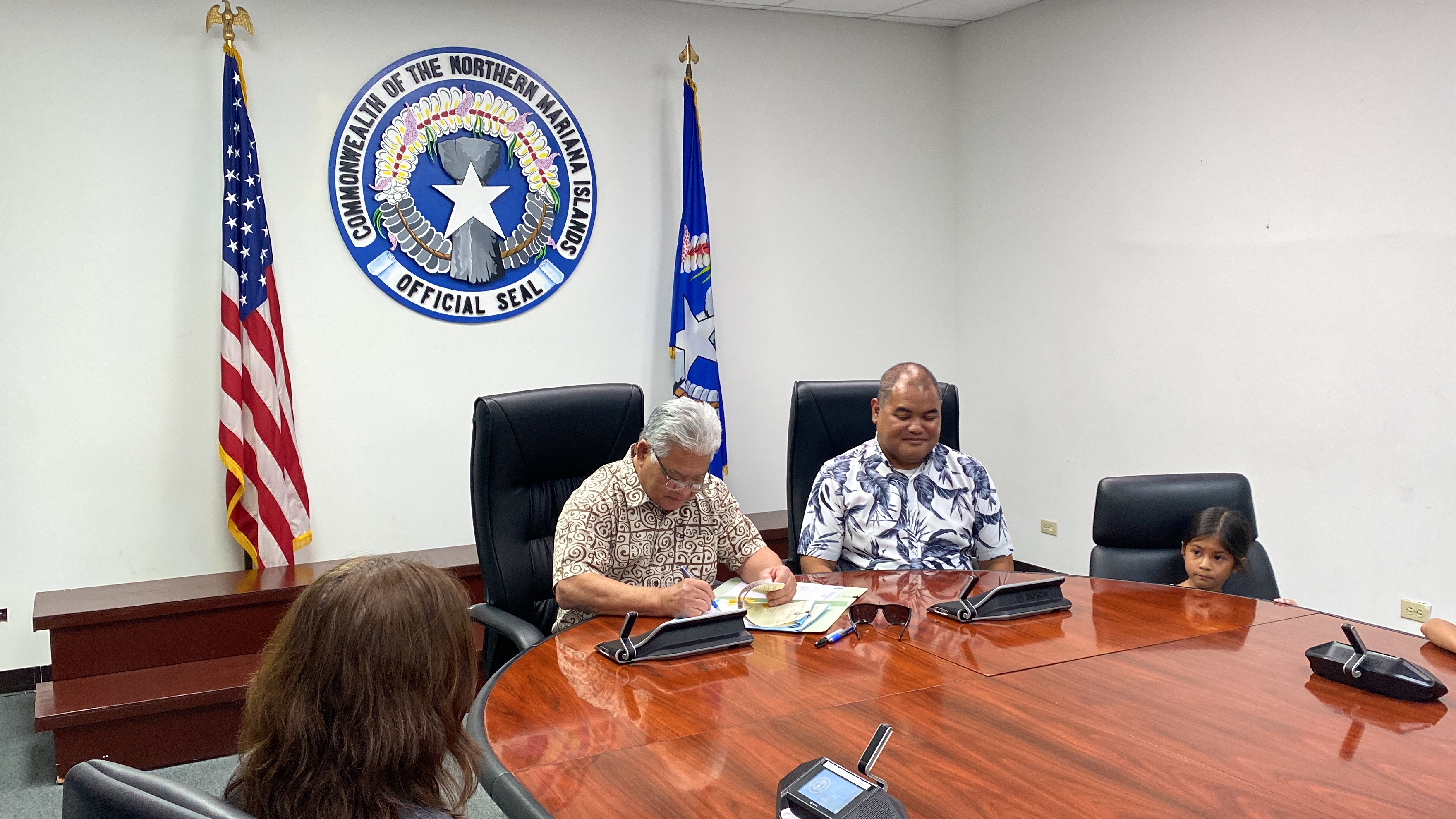Gov. Arnold Palacios, left, signs H.B. 23-47 into law as its author, Rep. Malcom Omar, looks on.