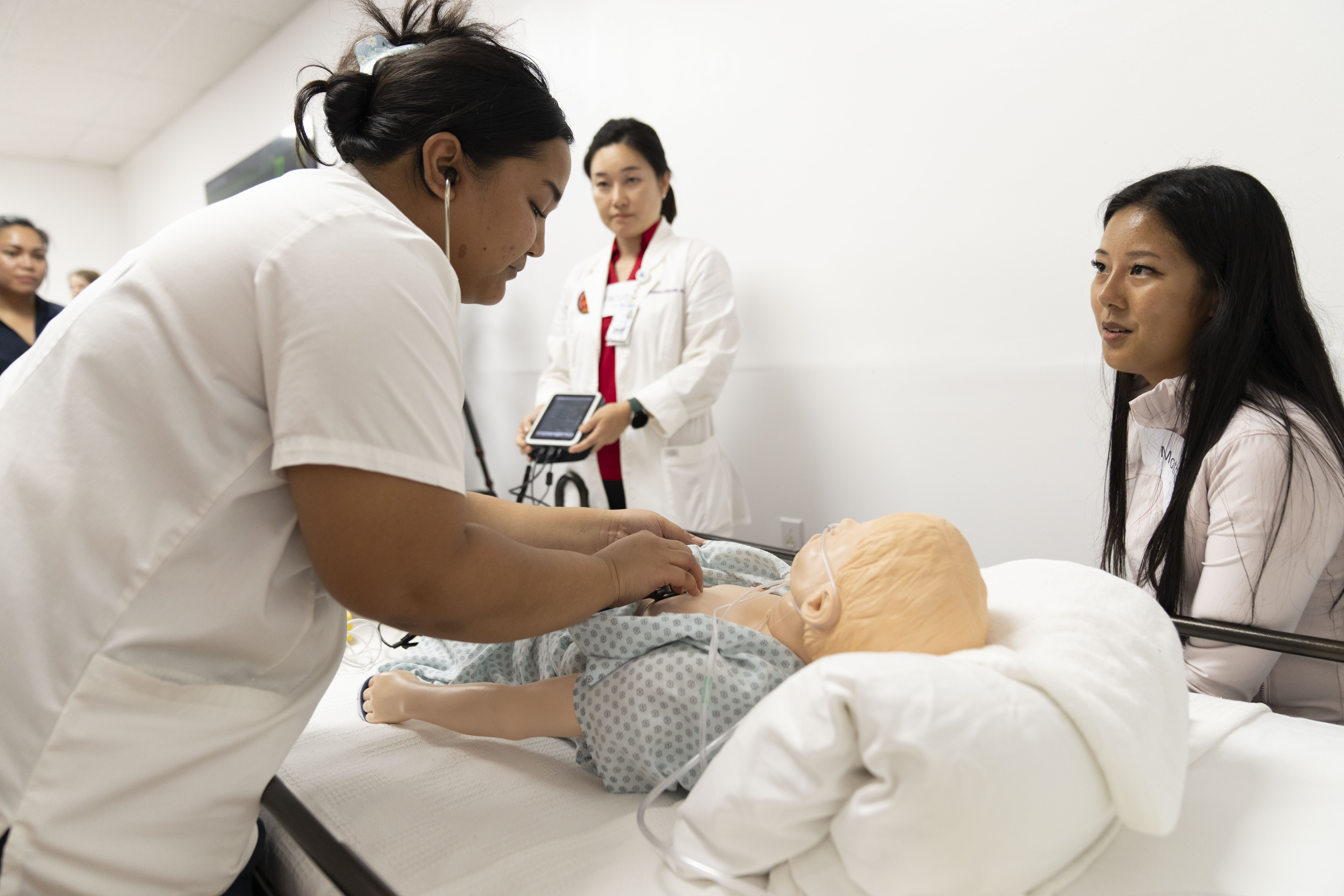 Northern Marianas College nursing students Tioni Reyes and Suah Sakisat, along with their instructor Dr. Ji Hye Lee, conduct a simulation in the newly opened Health Simulation Center at NMC. The center, which is funded by the NMC Area Health Education Center, is a modern facility designed to offer nursing and other allied health students a chance to practice in lifelike scenarios relevant to their future healthcare roles. It includes high-quality patient manikins in a simulated hospital room, equipped with a control room for the instructor. 
