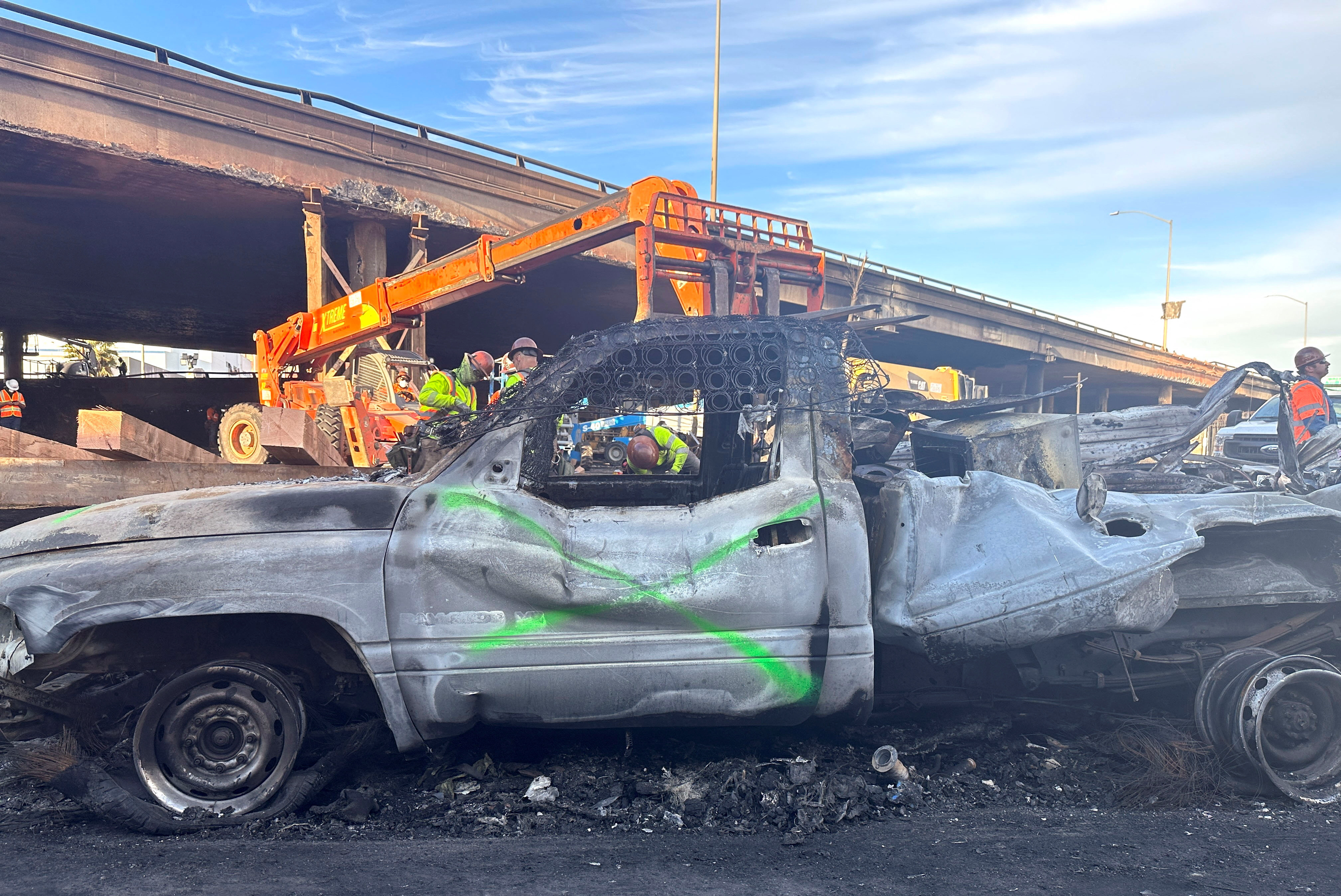 Crew members work in the area, where a fire erupted over the weekend, shutting down a heavily trafficked corridor in Los Angeles, California, U.S., November 13, 2023. 