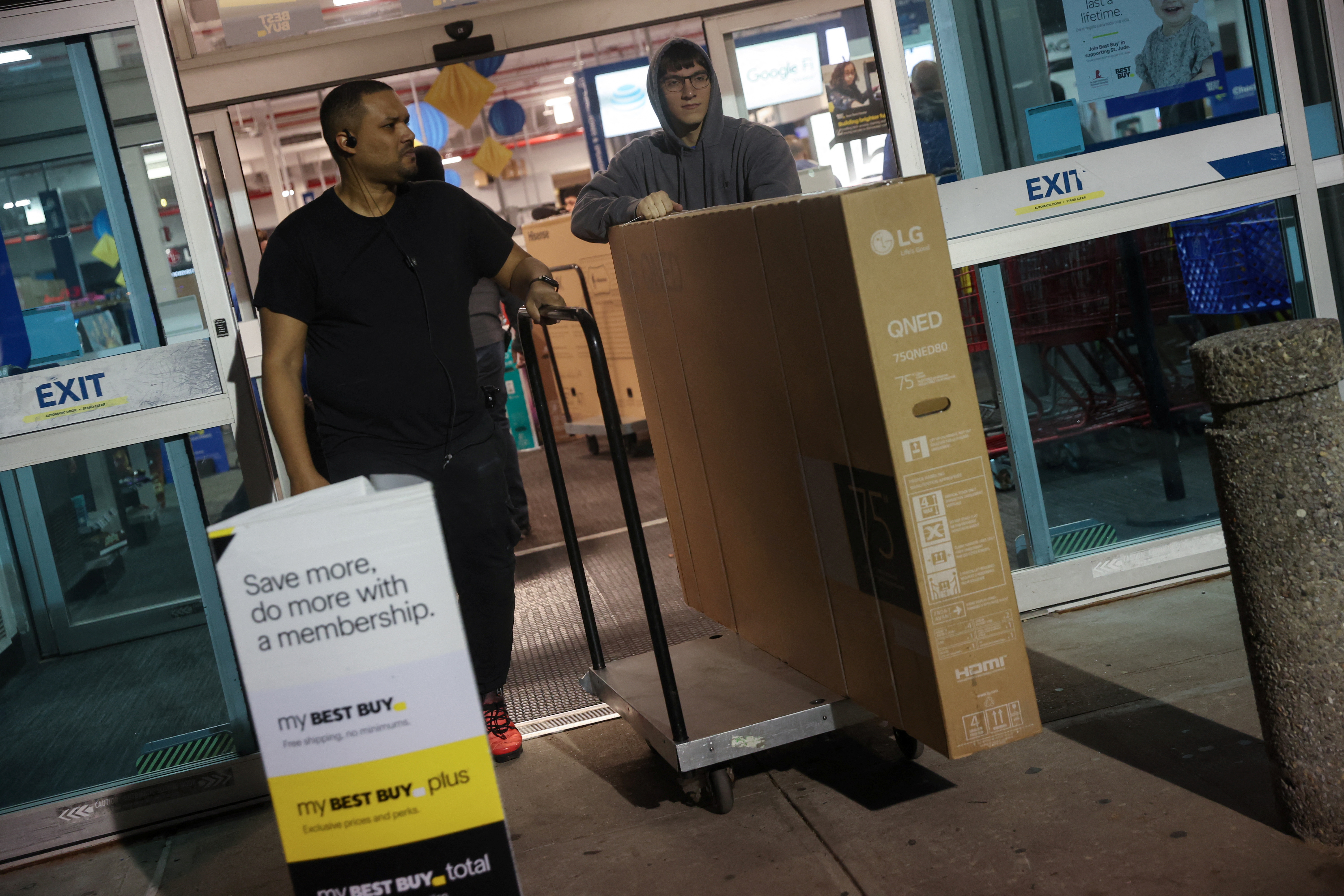 An employee at Best Buy electronics store helps to move out a television after a shopper made a purchase during Black Friday deals in Westbury, New York, U.S., November 24, 2023. 