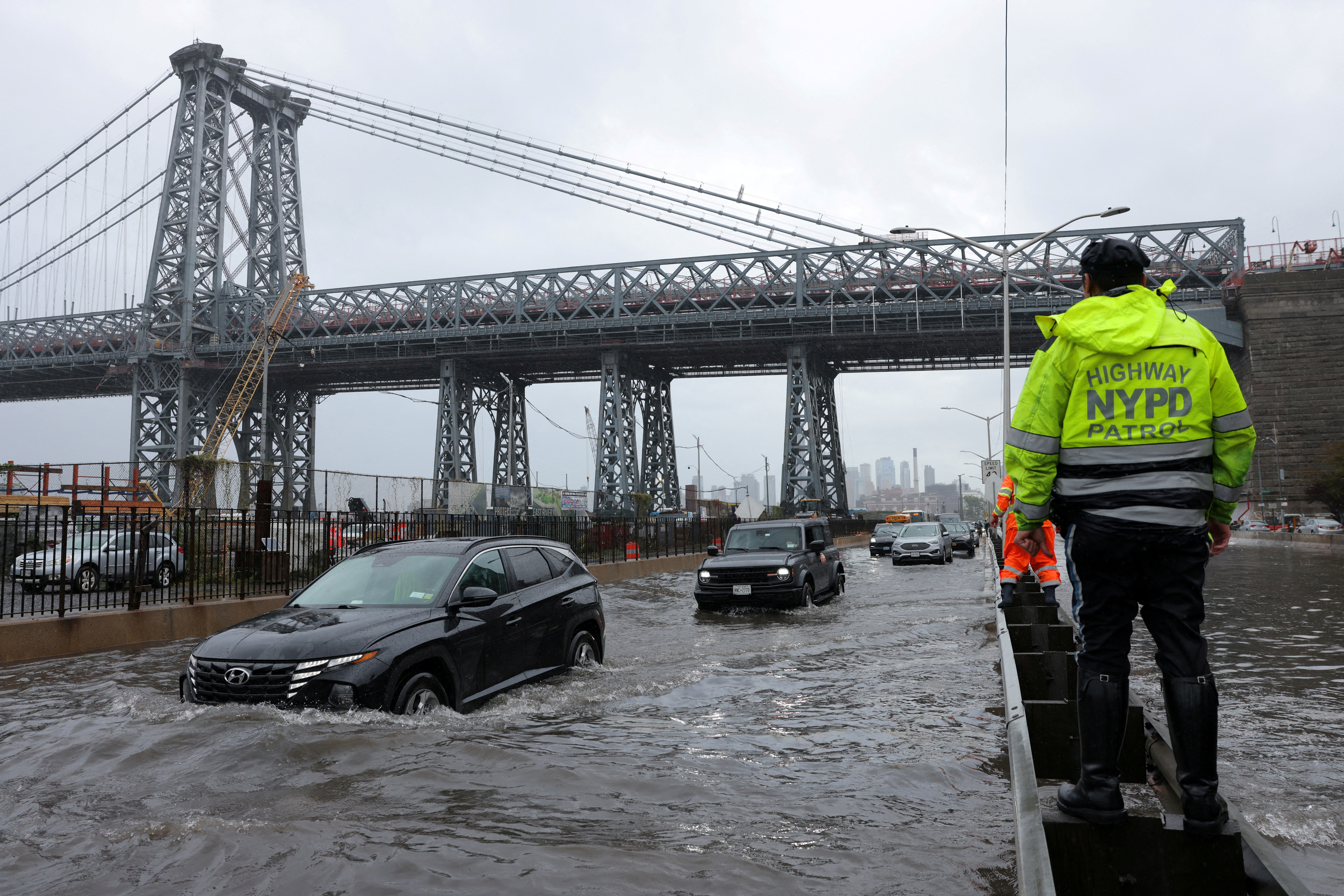 A police officer from the NYPD Highway Patrol looks to motorists drive through a flooded street after heavy rains as the remnants of Tropical Storm Ophelia bring flooding across the mid-Atlantic and Northeast, at the FDR Drive in Manhattan near the Williamsburg Bridge, in New York City, U.S., September 29, 2023. 