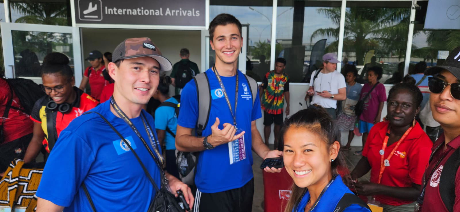Beach volleyball’s Andrew Johnson, left, and Logan Mister with athletics’ Tania Tan in the arrival area of the Honiara International Airport on Saturday.
