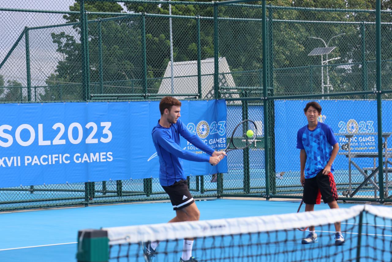 Colin Ramsey, left, hits the ball, while teammate June Yu looks on during training Thursday at the National Tennis Center in Honiara, the Solomon Islands.