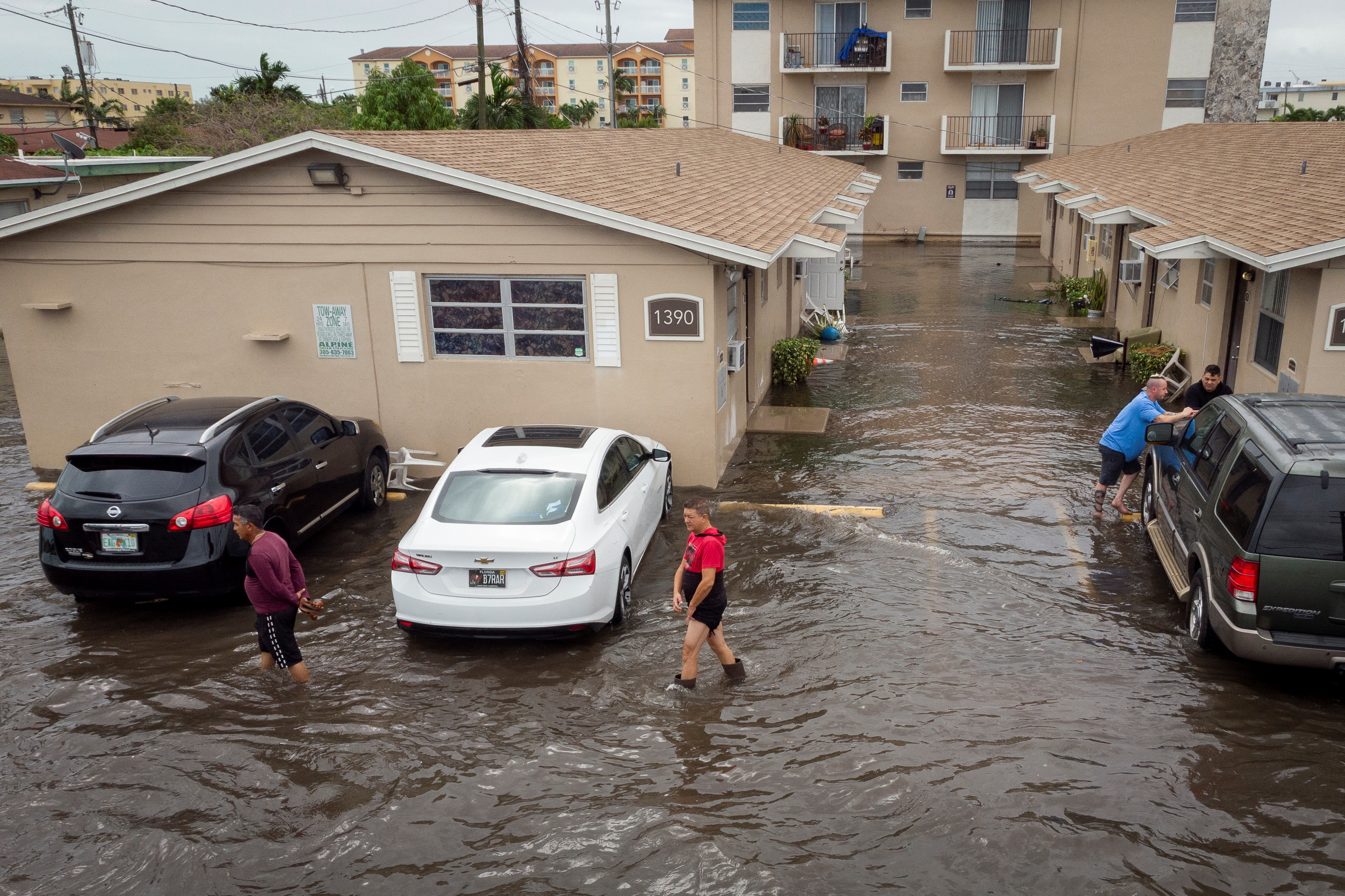 People walk in a flooded parking lot at a condo in Hialeah, Florida, U.S., November 16, 2023.