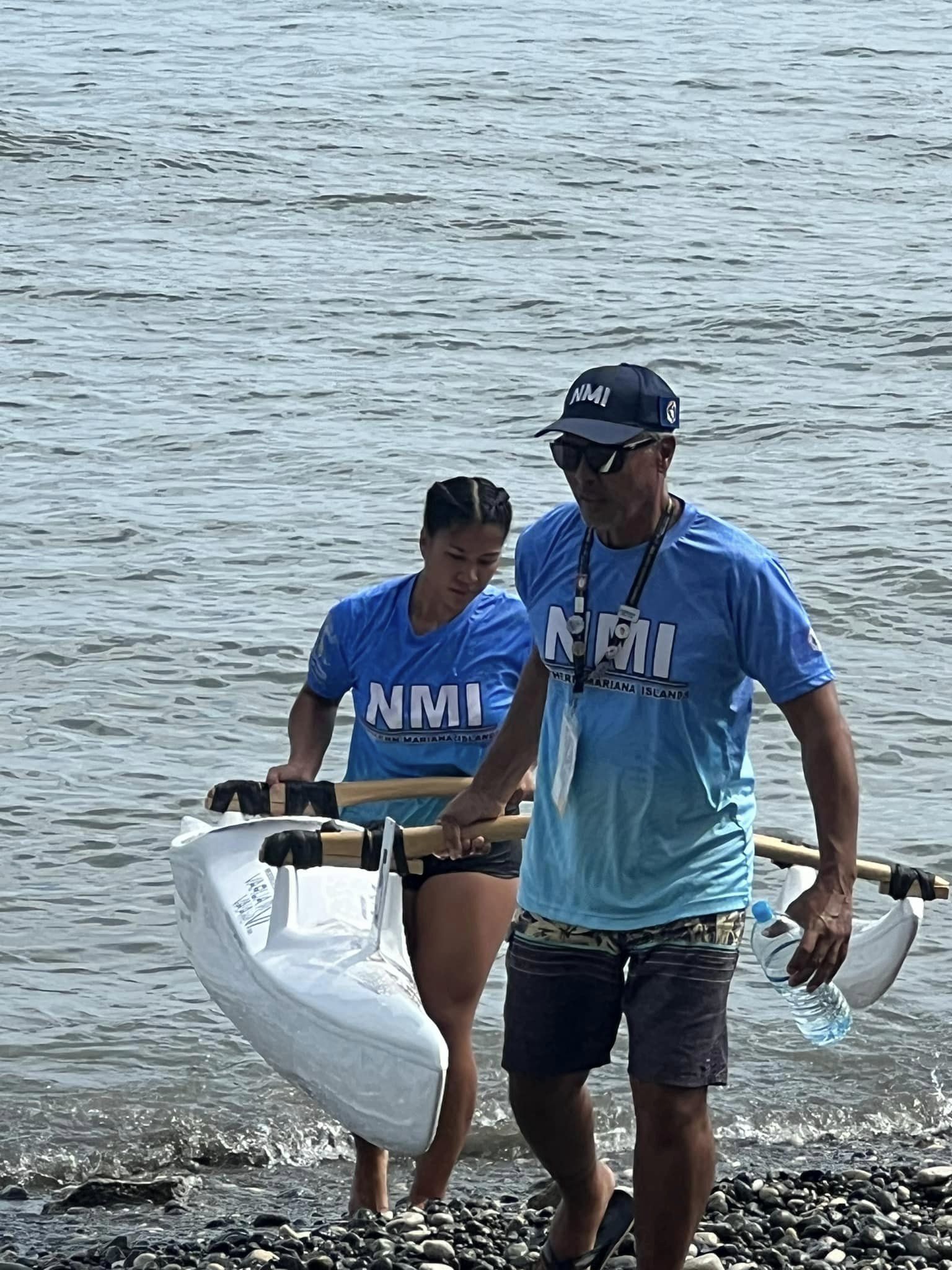 NMI team manager Joseph Weaver, right, assists paddler Jenisha Dubrall in bringing the V1 out of the water following the 500m race Monday at the DC Park in Honiara, the Solomon Islands.