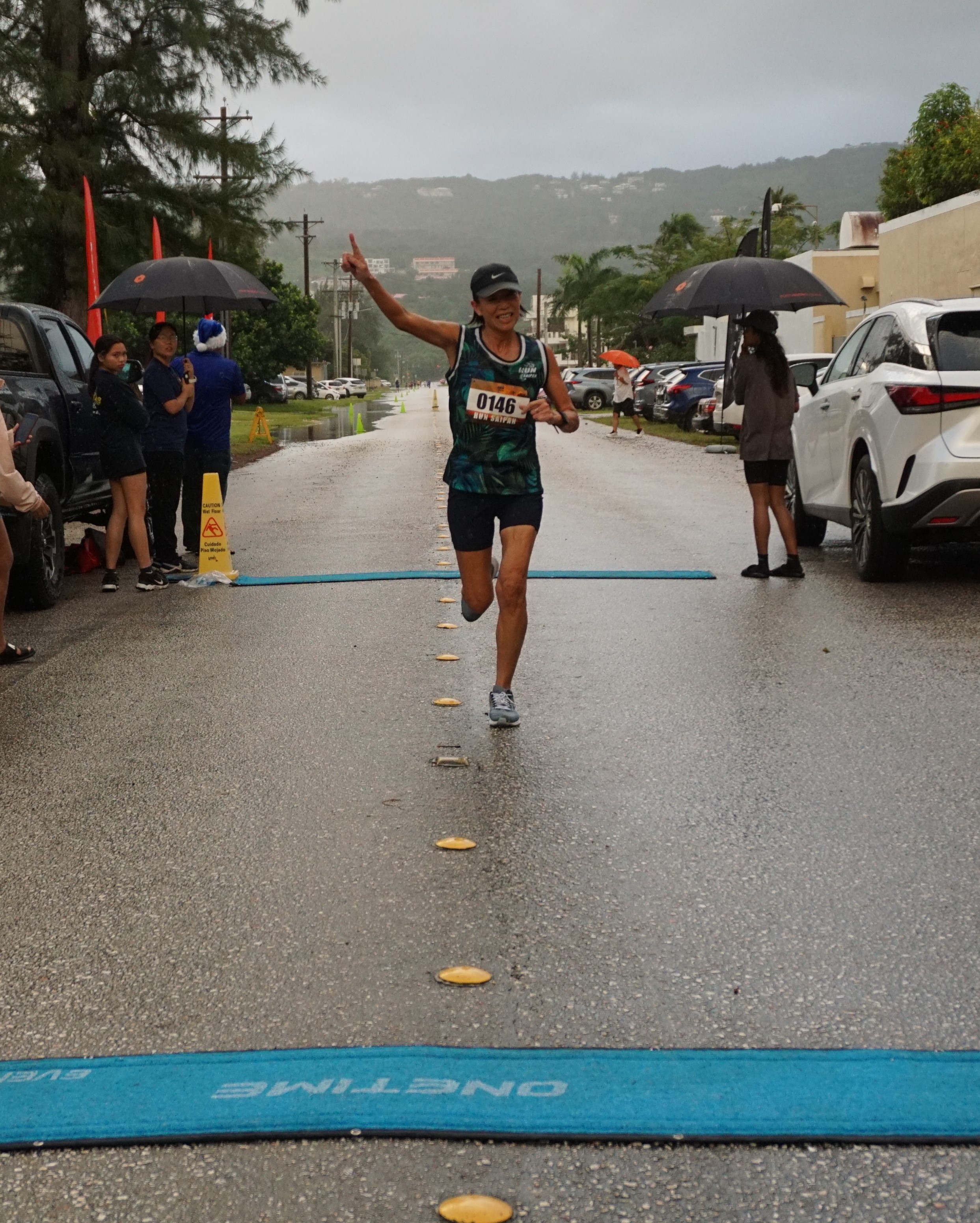 Noriko Jim celebrates as she finishes first overall in the women's division of the AK 5K Fun Run on Saturday at Micro Beach.