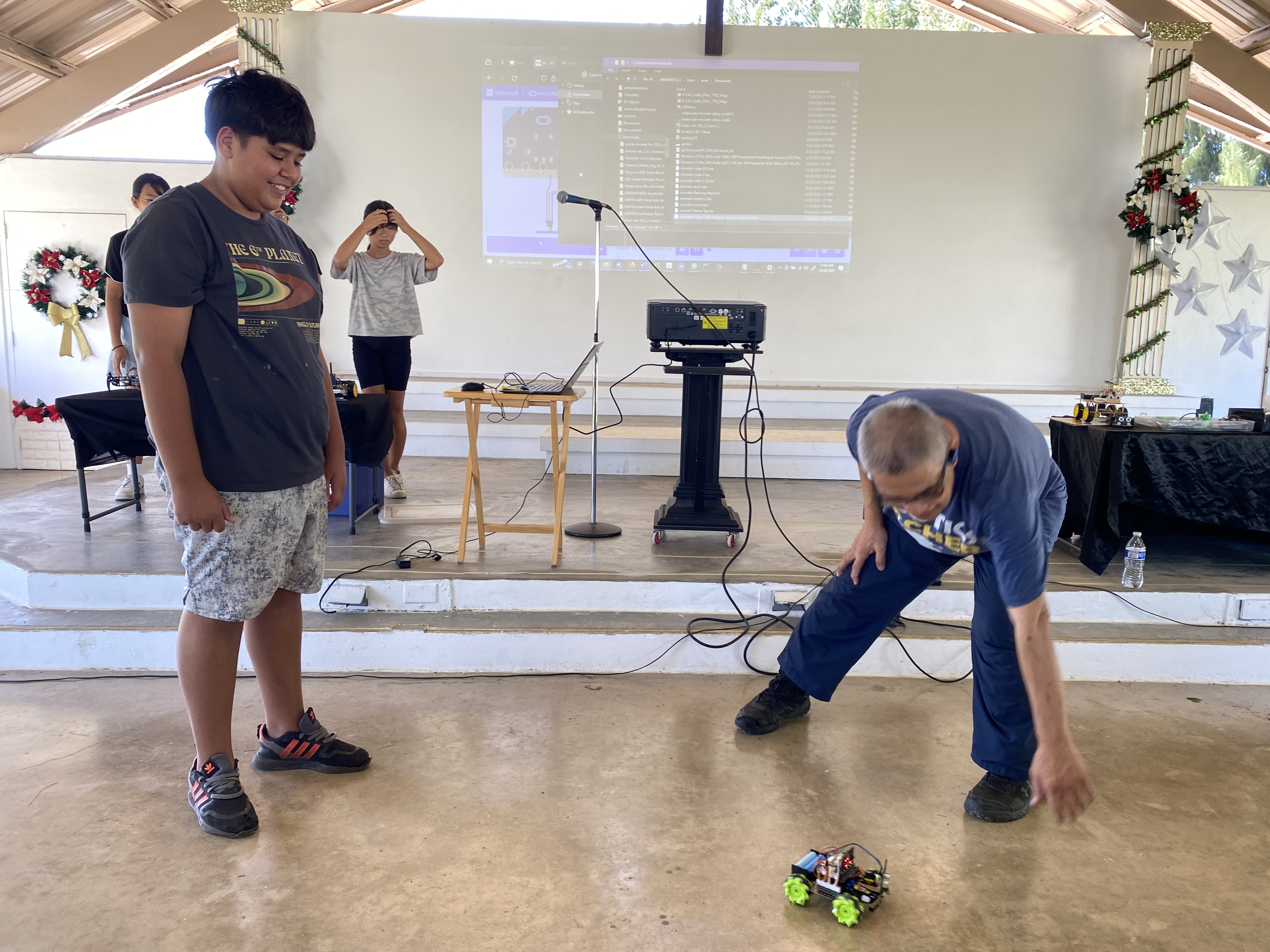 Sam Pangelinan, left, and Arnel Gruspe demonstrate the robot “pet” that Sam programed in class. The robot will follow someone when it is placed at a specific distance, and stop when it gets too close to a person. 