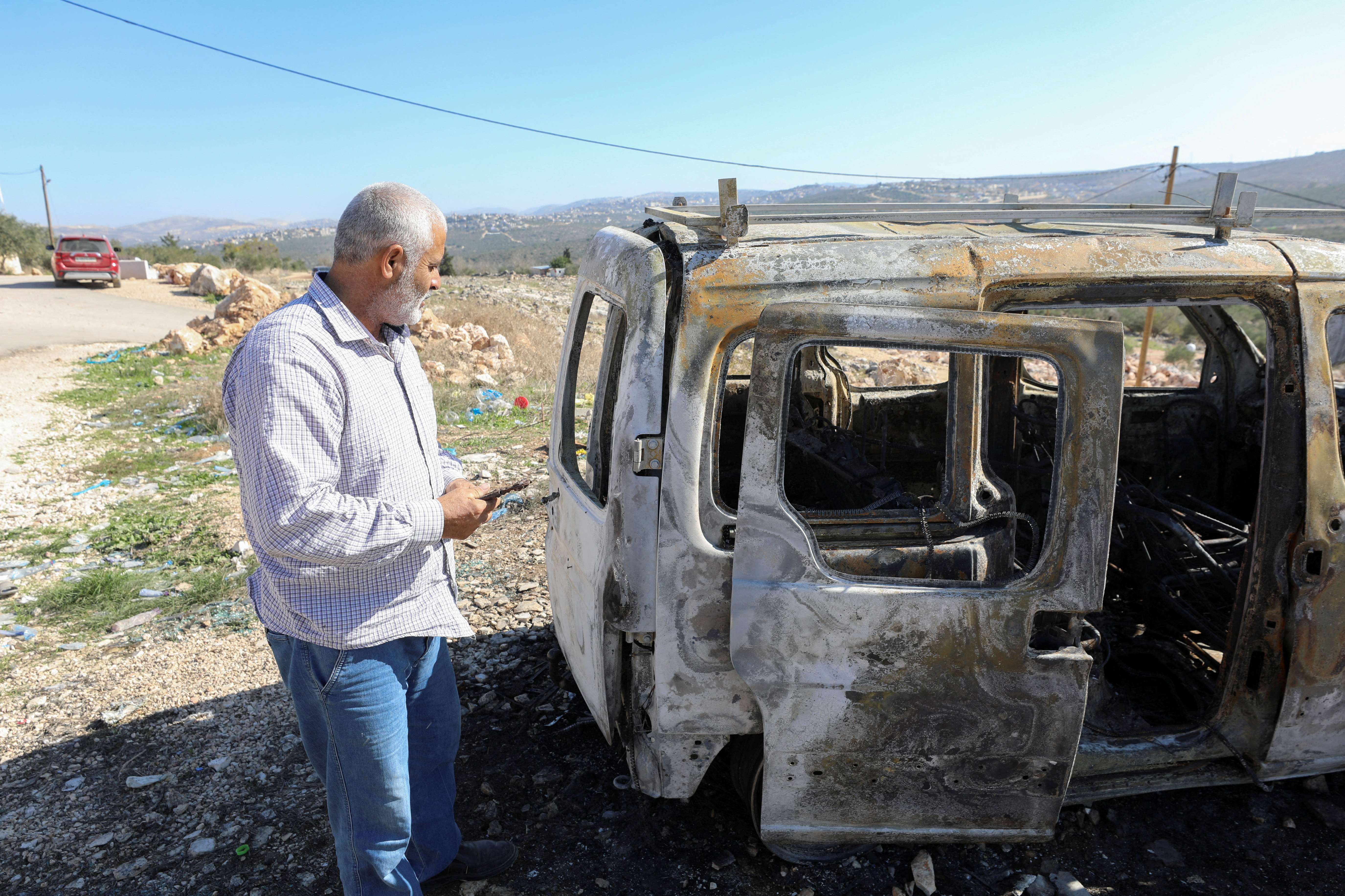 A Palestinian checks a car burned in Israeli settlers raid near Salfit in the Israeli-occupied West Bank December 3, 2023. 