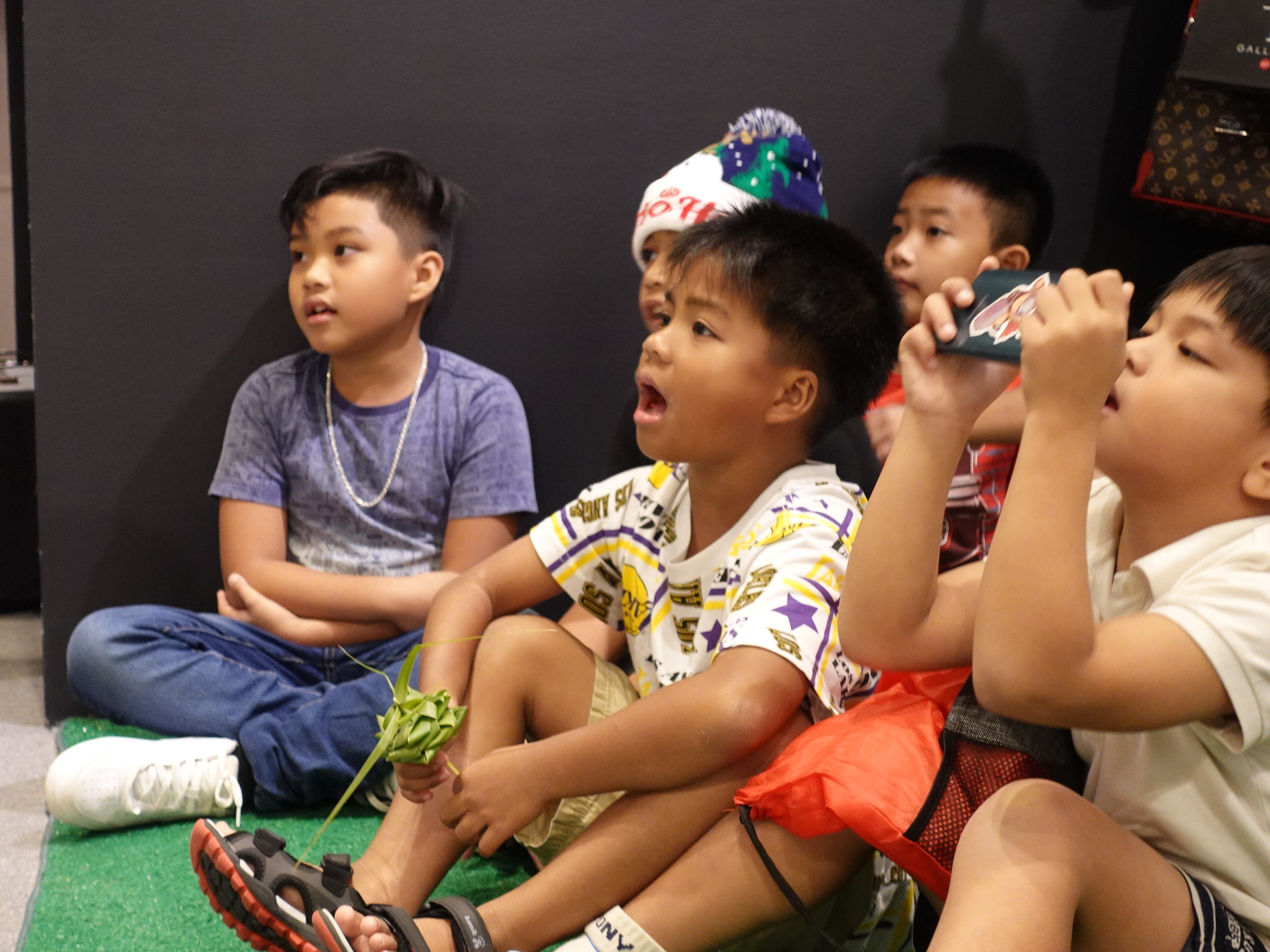 Youth audience members sing along with carolers at the 19th Annual Christmas in the Marianas on Dec. 9, 2023, at T Galleria in Garapan, Saipan.
