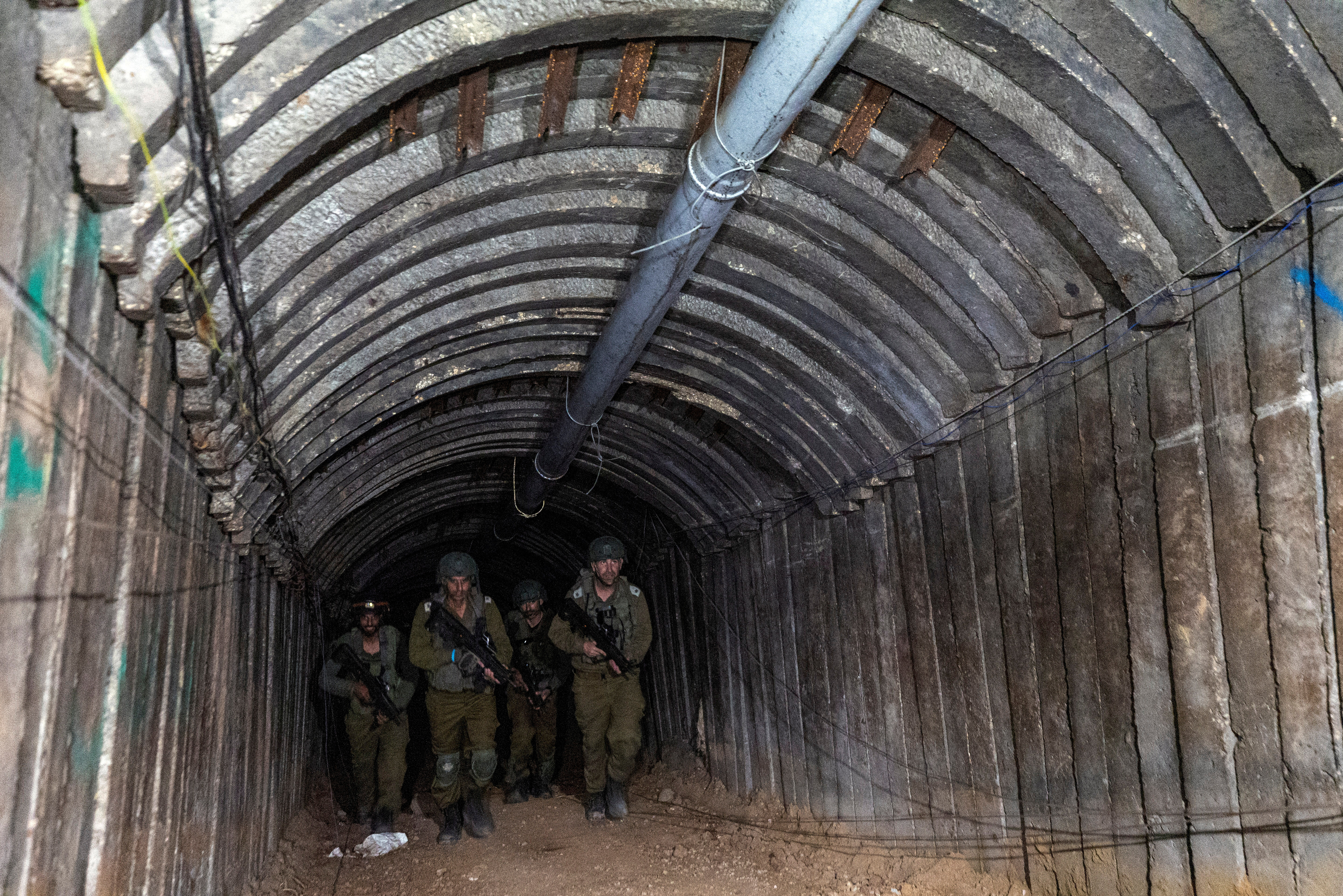 Israeli soldiers walk through what Israel's military says is an iron-girded tunnel designed by Hamas to disgorge carloads of Palestinian fighters for a surprise storming of the border, amid the Israeli army's ongoing ground operation against Palestinian Islamist group Hamas, close to Erez crossing in the northern Gaza Strip, December 15, 2023. 
