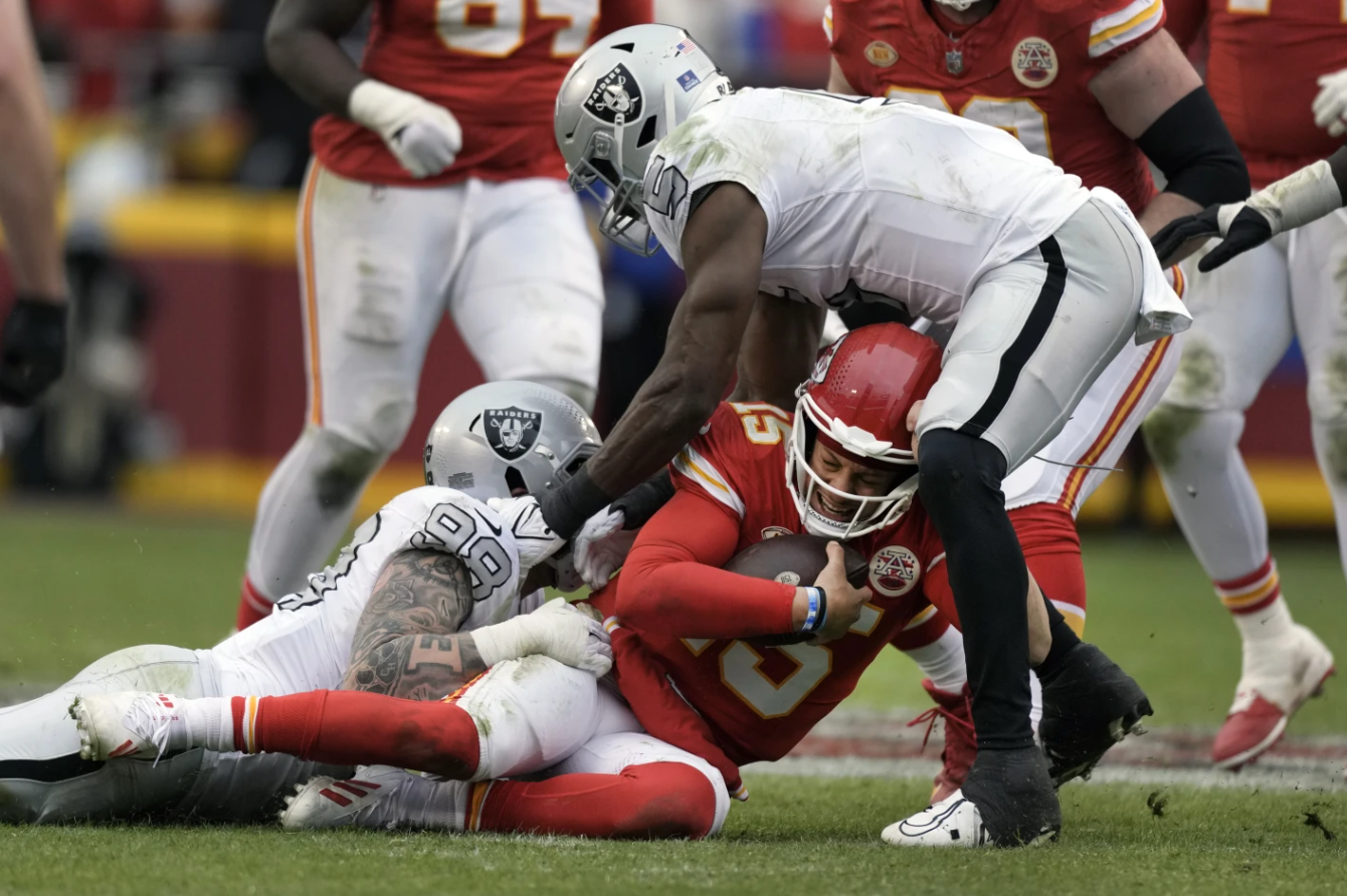 Kansas City Chiefs quarterback Patrick Mahomes (15) is stopped by Las Vegas Raiders defensive end Maxx Crosby (98) and linebacker Divine Deablo (5) during the second half of an NFL game Monday, Dec. 25, 2023, in Kansas City.