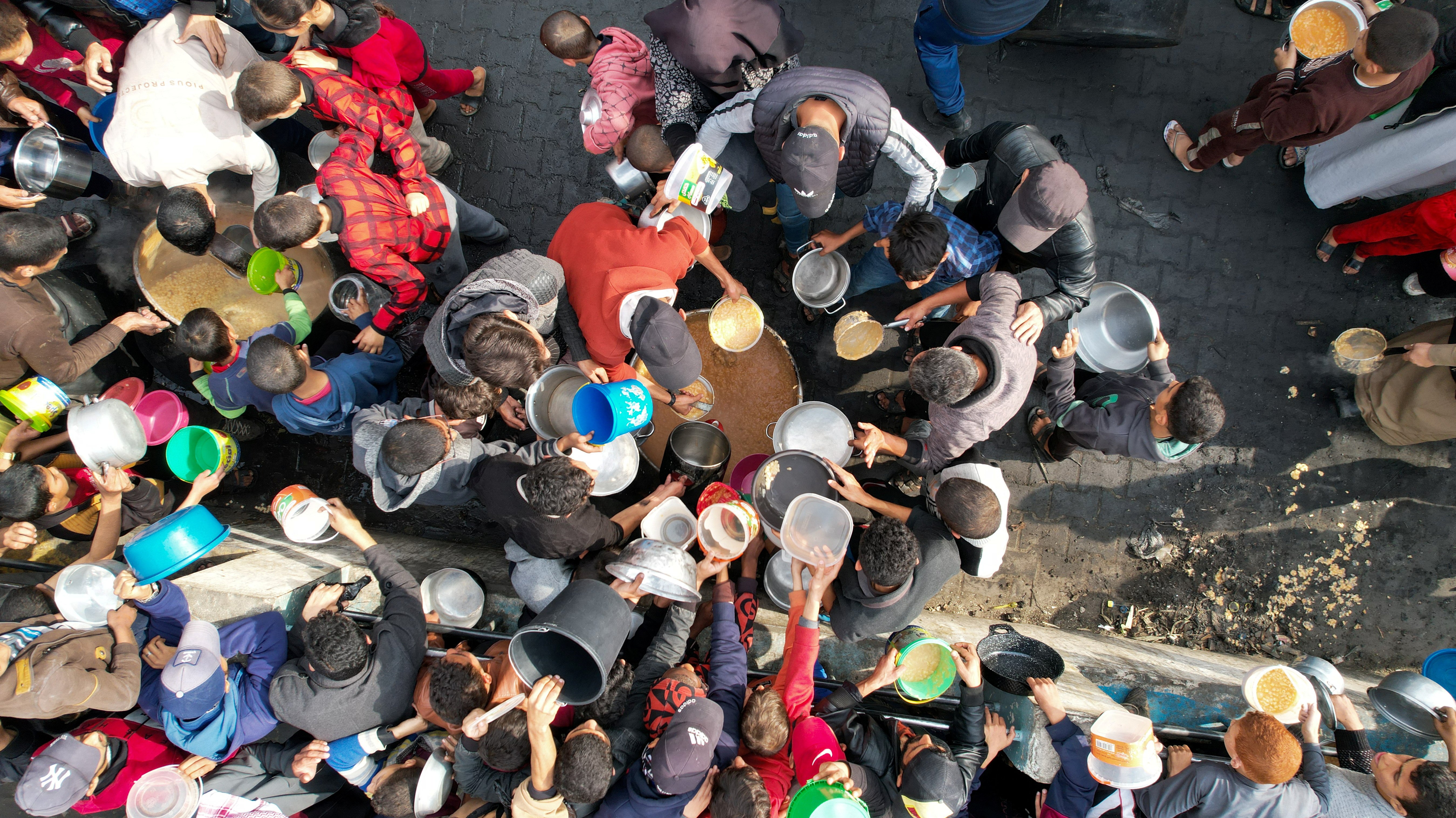 Palestinians gather to receive food cooked by a charity kitchen, amid the ongoing conflict between Israel and the Palestinian Islamist group Hamas, in Rafah in the southern Gaza Strip December 17, 2023. 