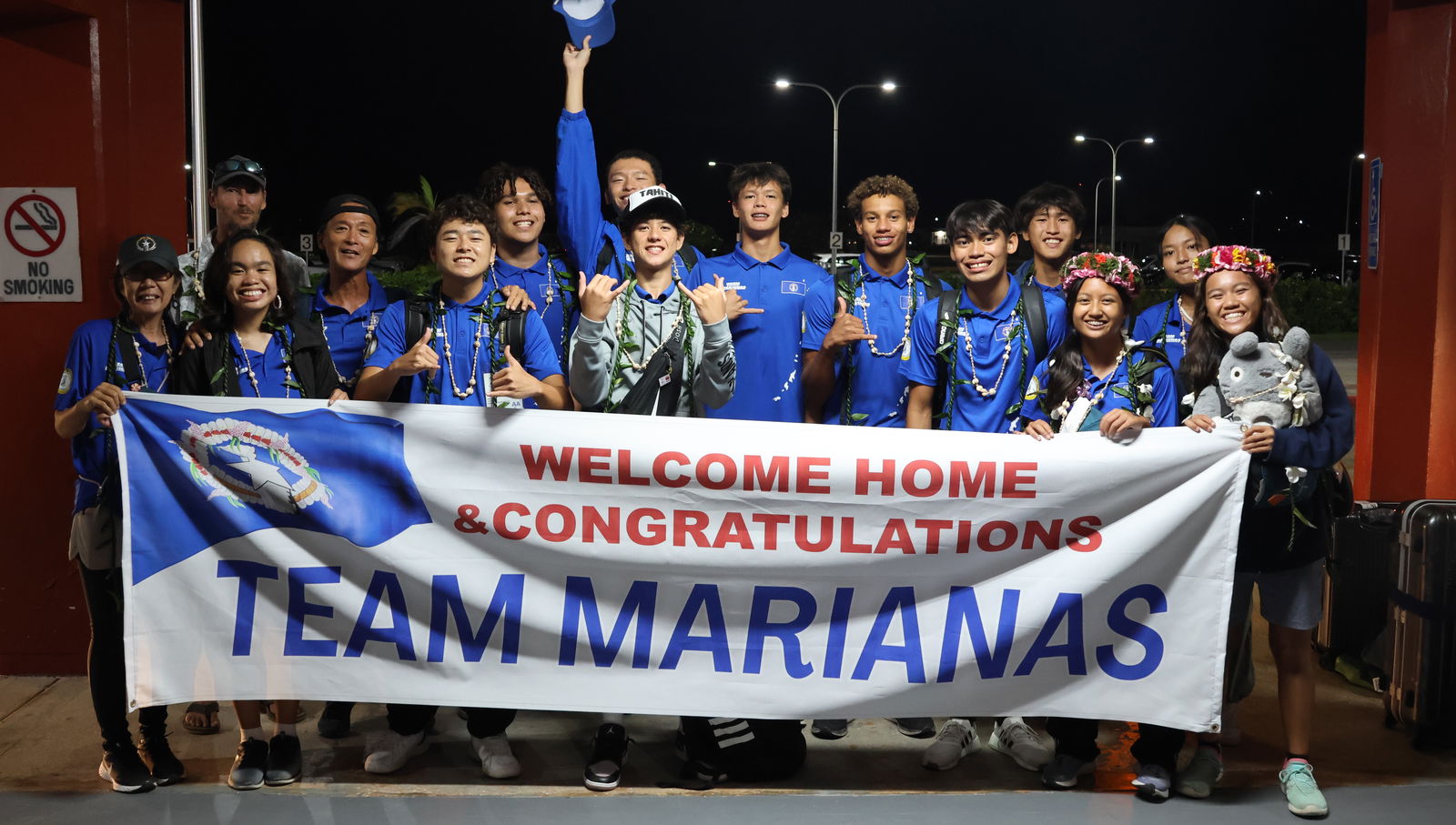 NMI swim team members and officials pose for a photo after receiving a warm welcome at the Francisco C. Ada/Saipan International Airport on Sunday night.