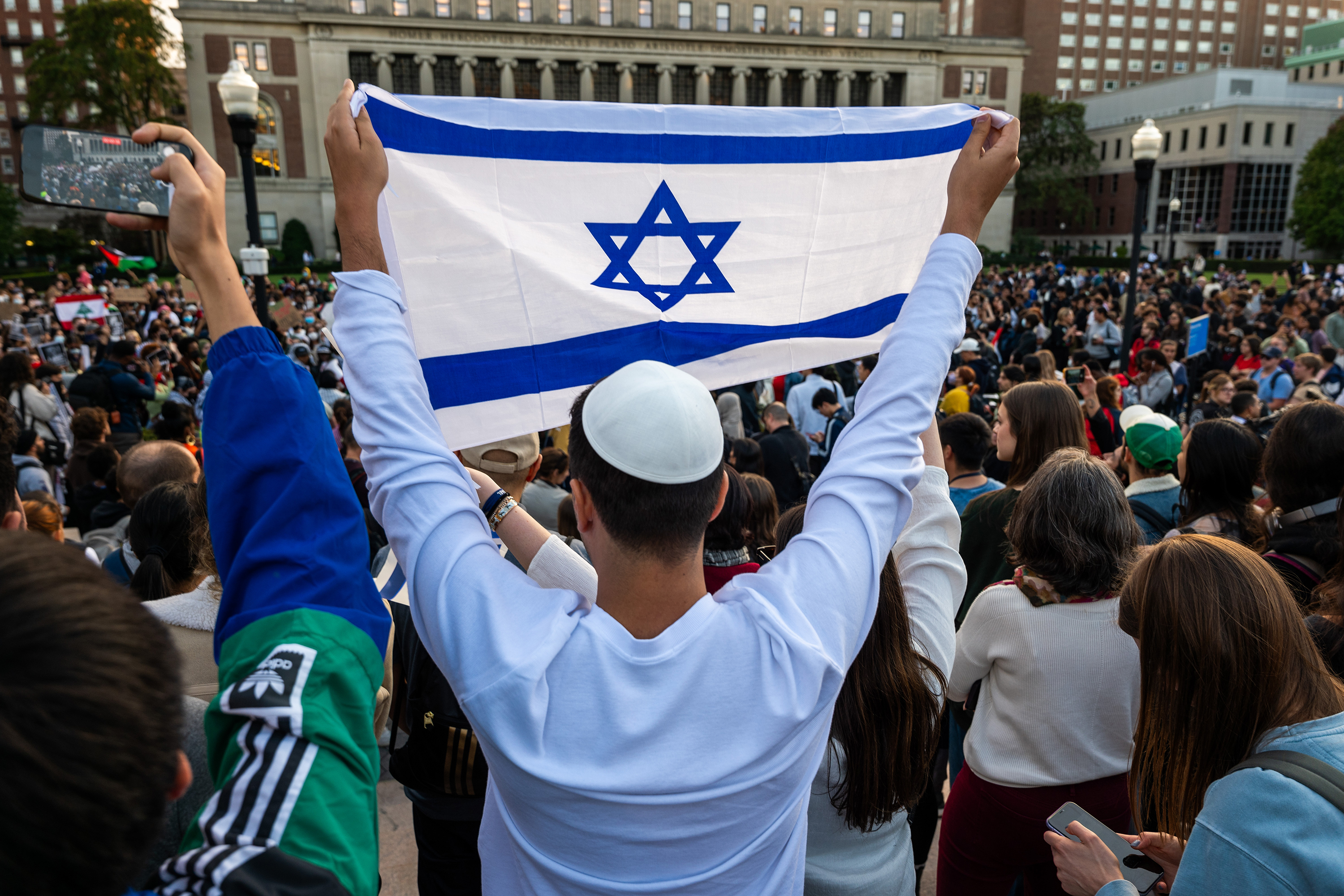 A man holds up an Israeli flag as Columbia students participate in a rally in support of Palestine at the university on Oct. 12, 2023, in New York. A Georgia middle school teacher in December 2023 is facing charges after he allegedly threatened to behead a Muslim student who told him the Israeli flag in his classroom was offensive. (Spencer Platt/Getty Images/TNS)