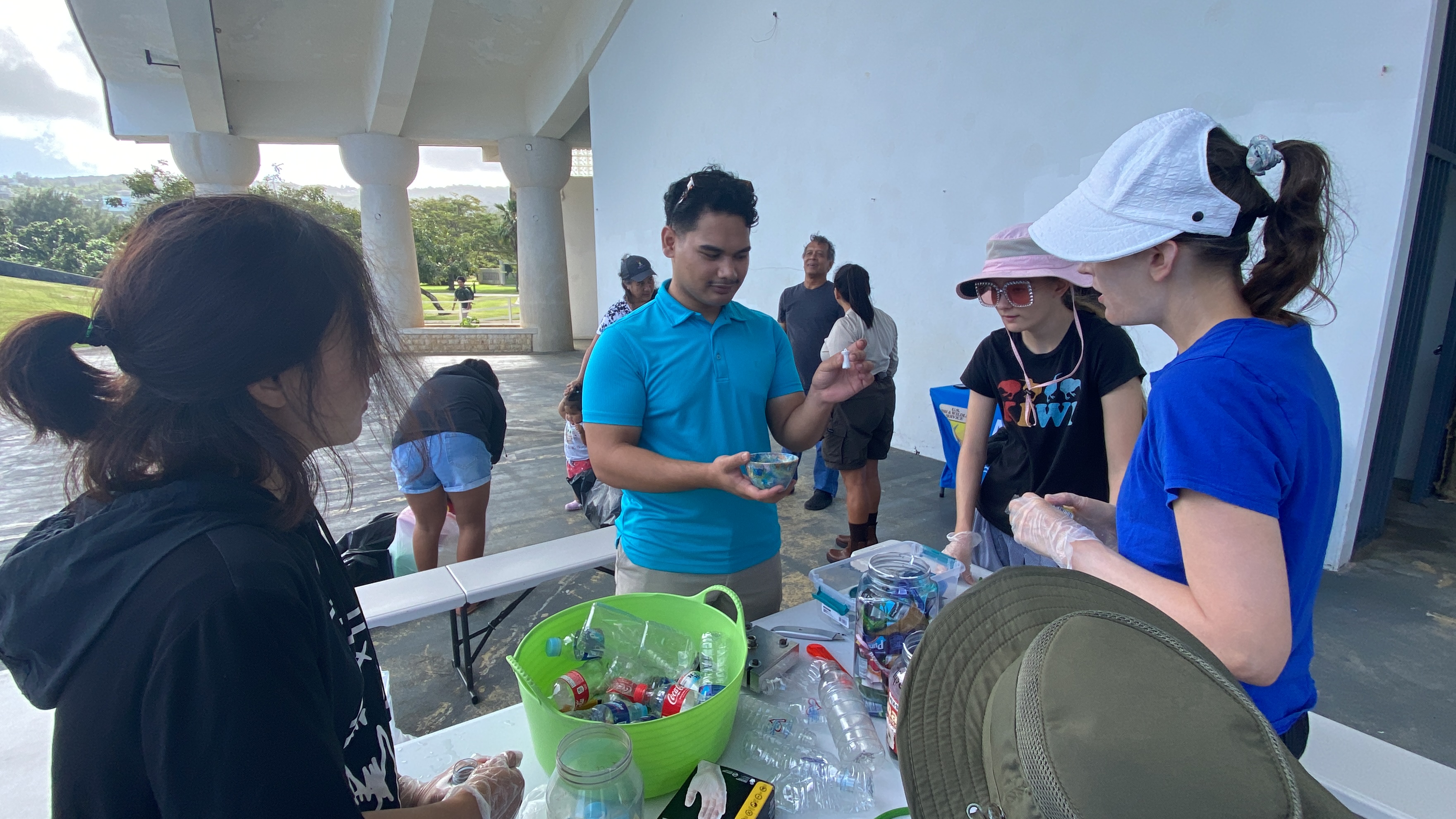 Volunteers take a break from sorting plastics to listen to Joseph Nekaifes explain where the recycled plastics wind up after they go through the 3-in-1 Upcycling Machine.