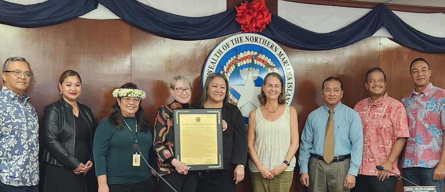 Former Attorney General Pam Brown-Blackburn, fourth left, holds a framed copy of Senate Resolution 23-11 as she poses with senators  and Friends of the Mariana Trench Executive Director Laurie Peterka, fourth right, during a break from a Senate session on Nov. 24, 2023.