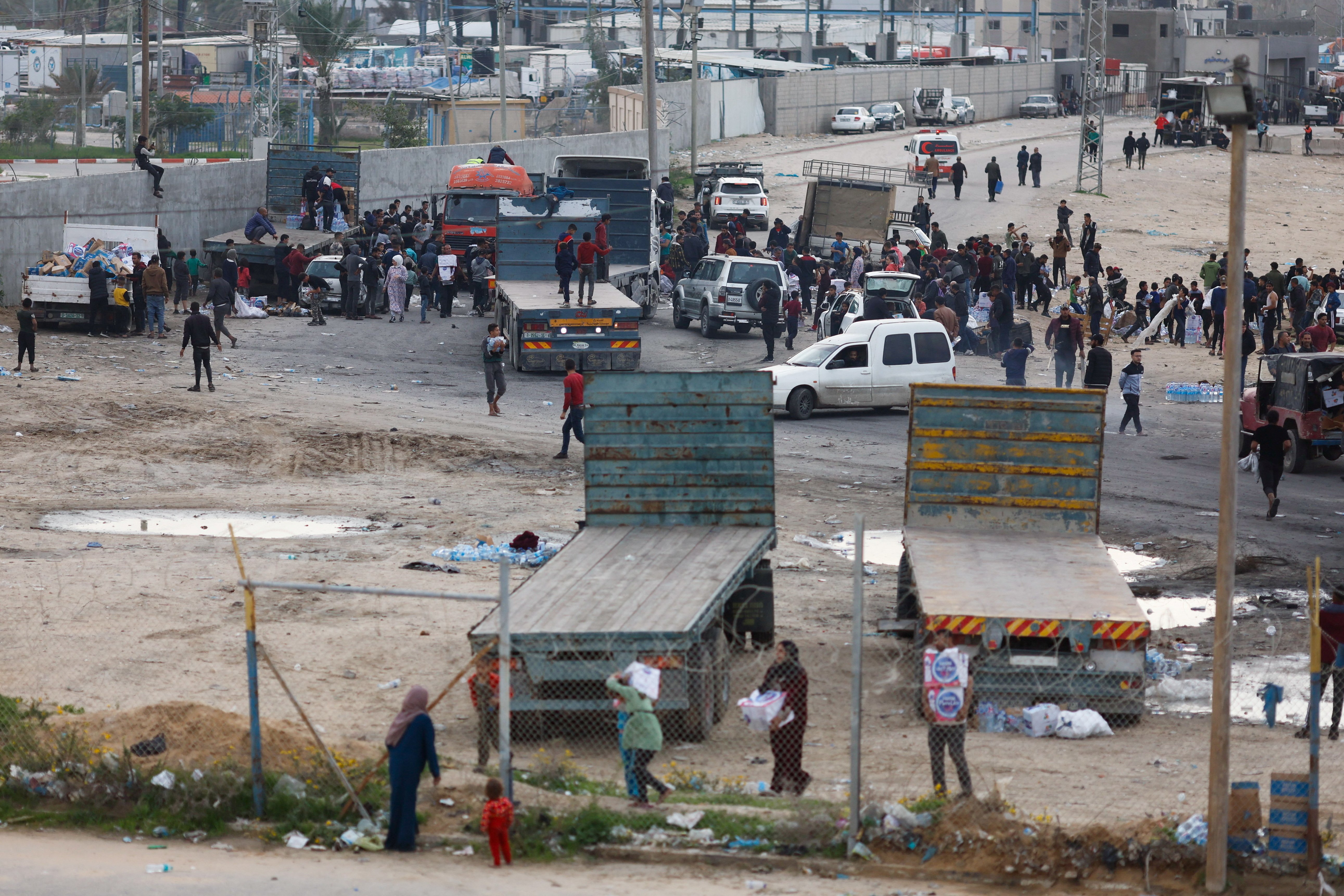 Palestinians gather to unload boxes with bottles of water from trucks, amid drinking water shortages, as the ongoing conflict between Israel and the Palestinian Islamist group Hamas continues, at Rafah border with Egypt, in the southern Gaza Strip December 17, 2023. 